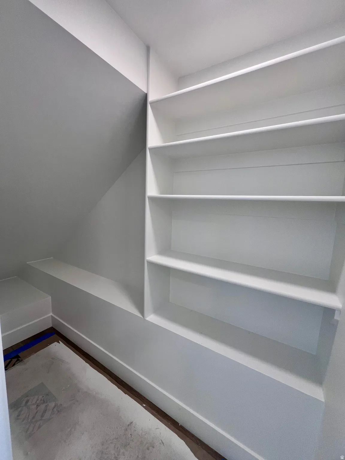 Built-in shelving unit featuring multiple open shelves, a low built-in bench, and a slanted wall design