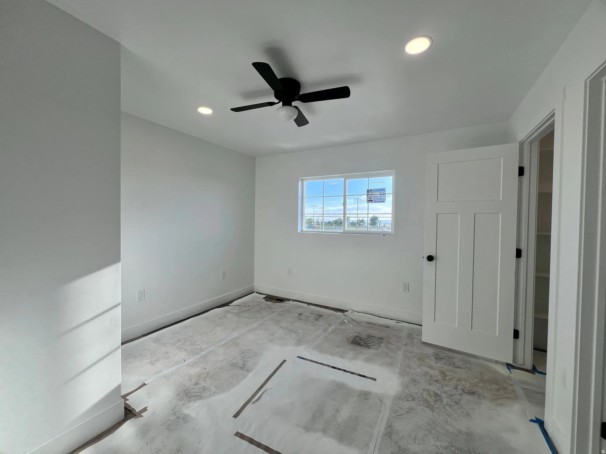 Room featuring recessed lighting, a modern ceiling fan with integrated lighting, a multi-pane window, and a paneled interior door with dark hardware