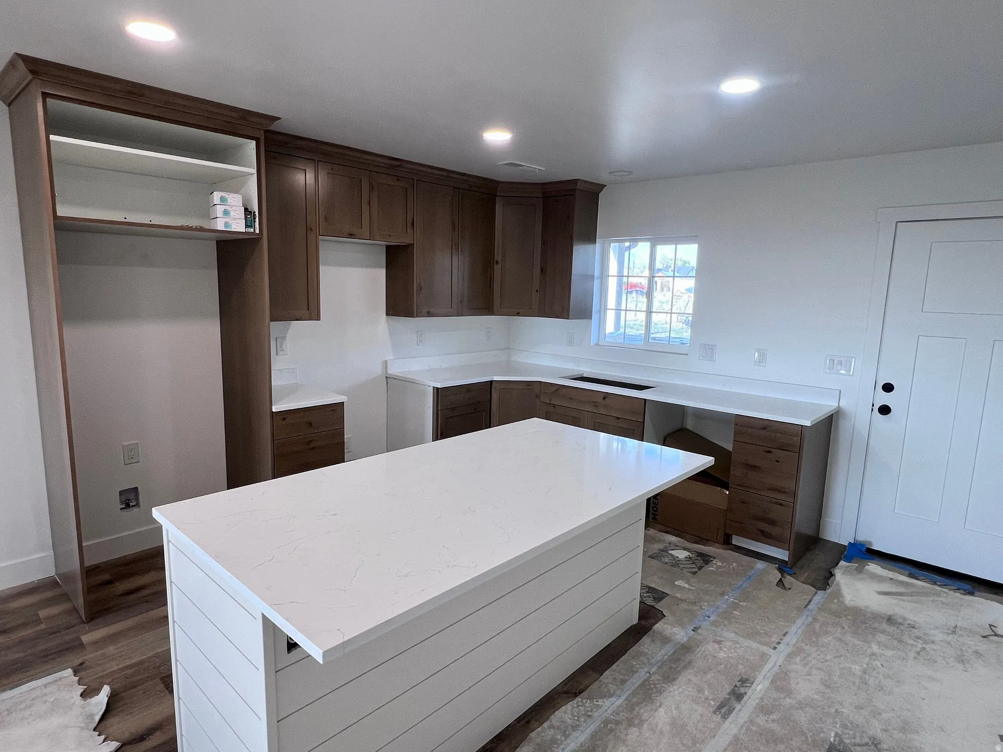 Kitchen featuring a central island with white shiplap paneling and a light-toned countertop