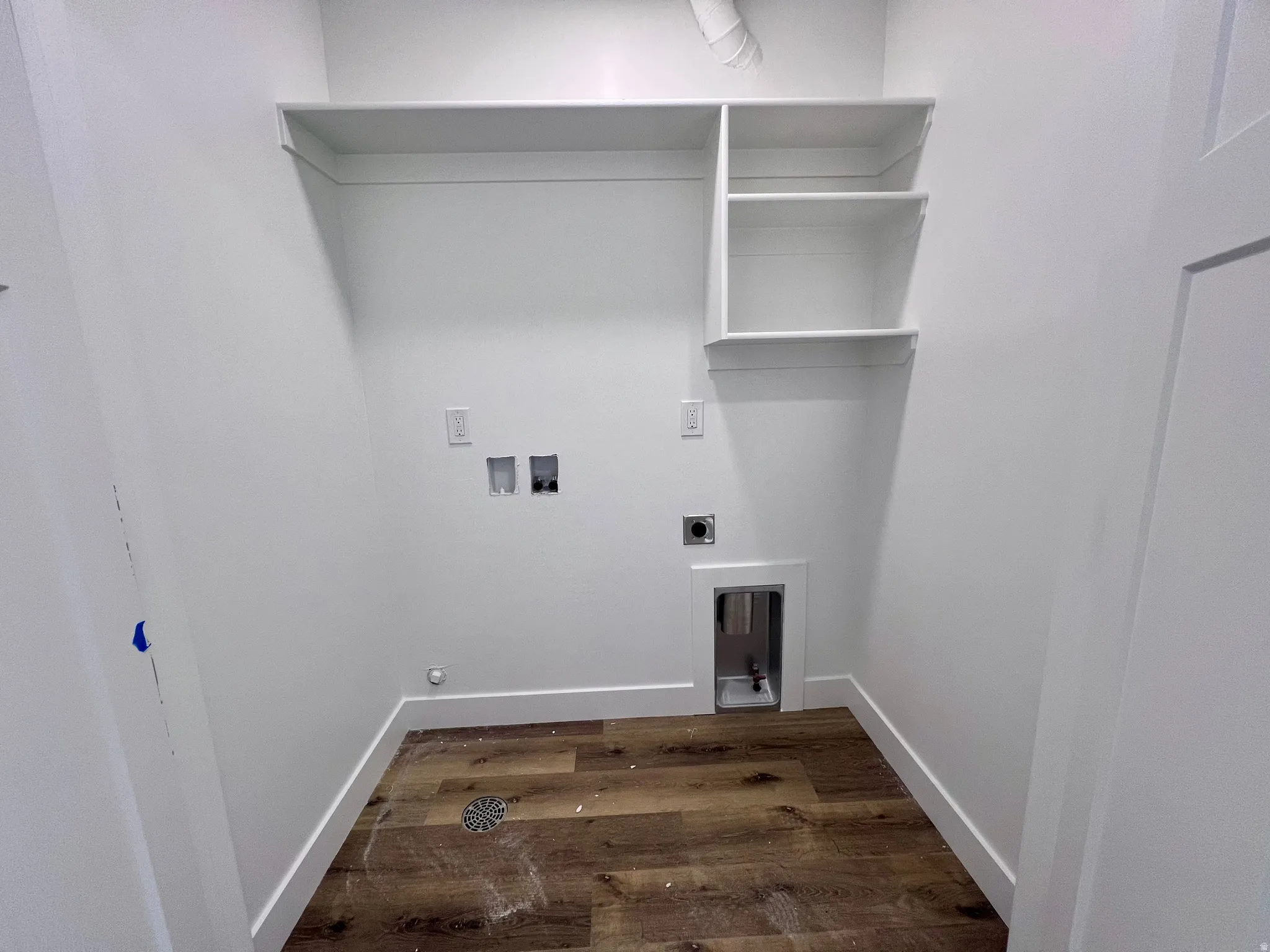 Dedicated laundry space featuring wood-finish flooring and white baseboards