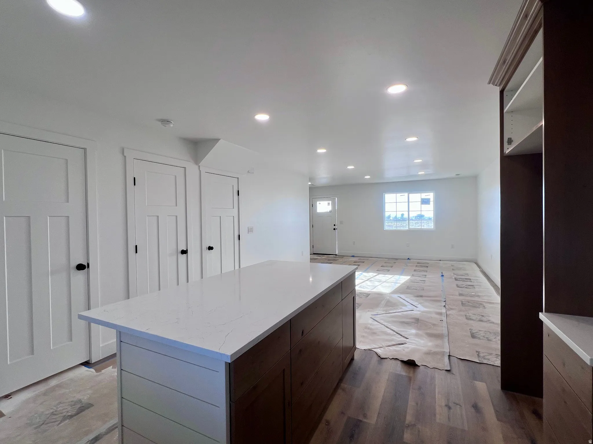 Kitchen island with a white quartz countertop, shiplap detailing, and wood-finish cabinetry