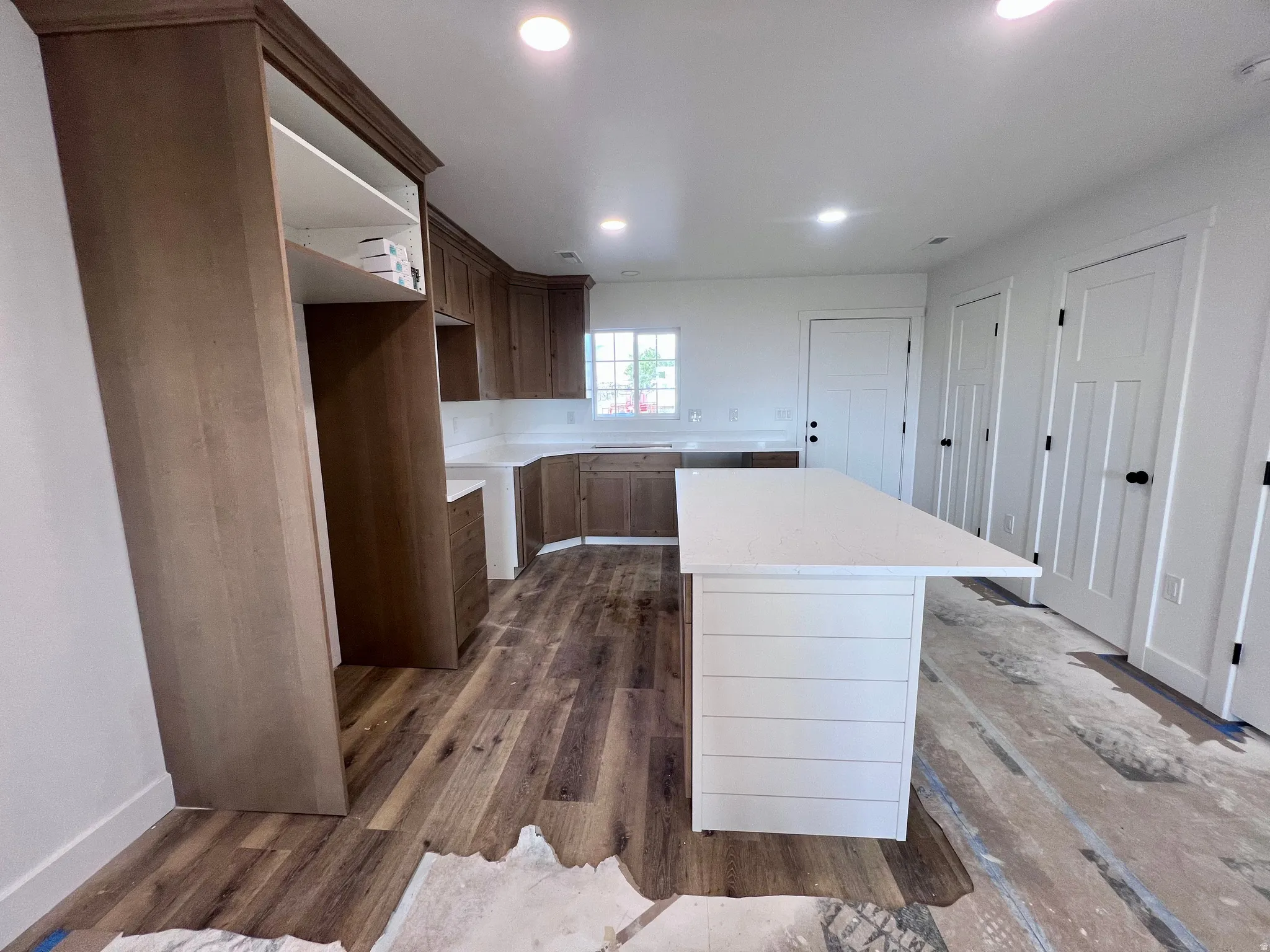 Kitchen featuring a white shiplap island with an extended countertop, wood-finish flooring, recessed lighting, and white shaker-style doors with black hardware