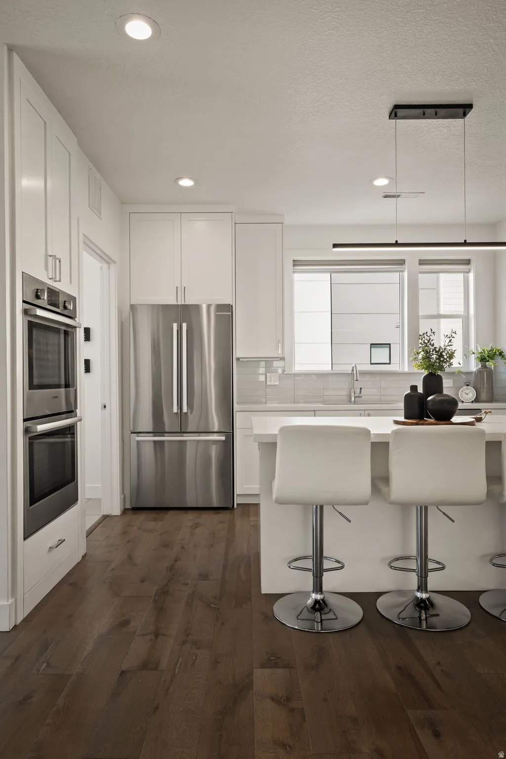 Kitchen featuring stainless steel appliances, white cabinetry, a kitchen breakfast bar, dark wood finished floors, and recessed lighting