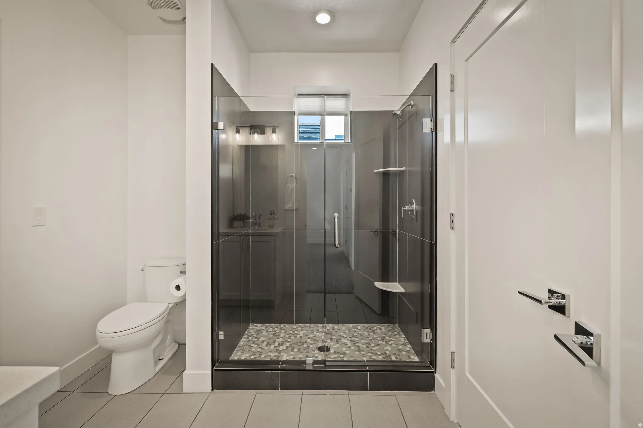 Full bath with a shower stall and light tile patterned floors