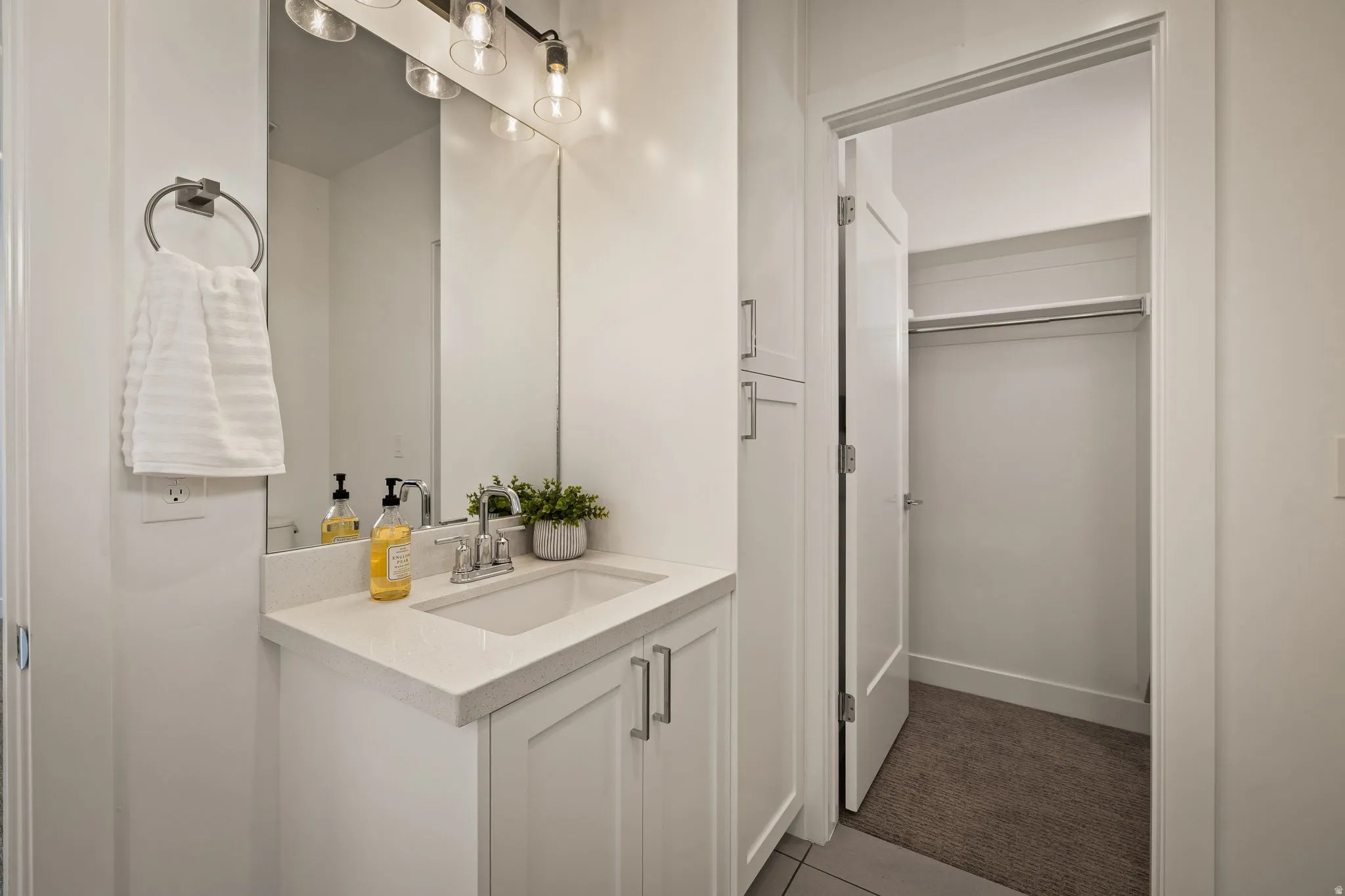 Bathroom with vanity, a walk in closet, dark tile patterned flooring, and dark carpet