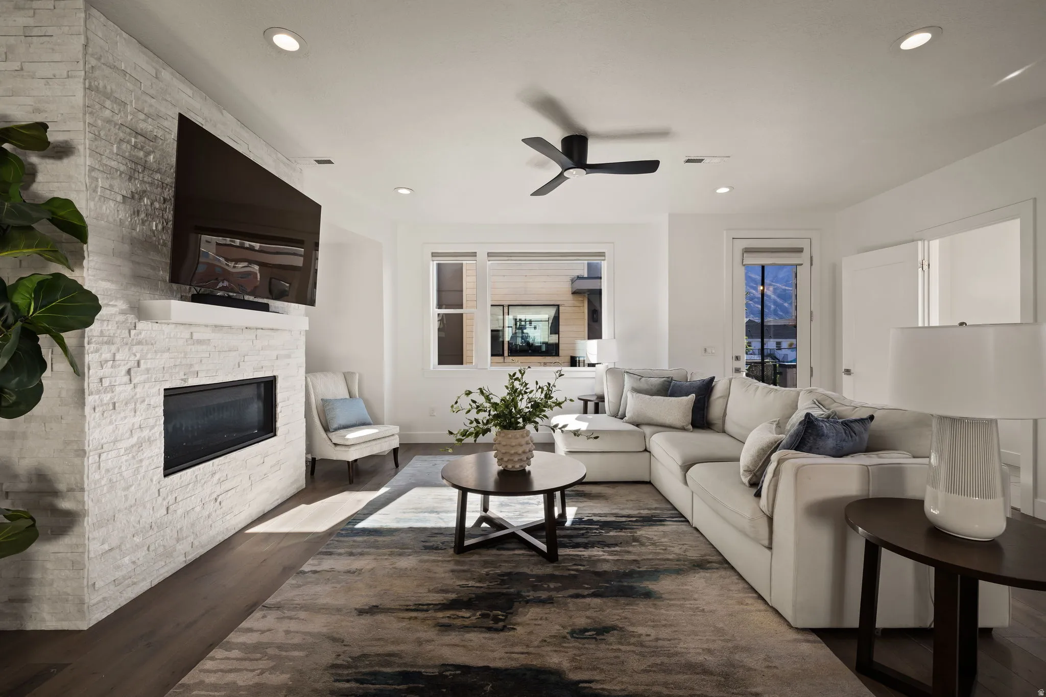 Living room featuring a fireplace, a ceiling fan, dark wood-type flooring, and recessed lighting