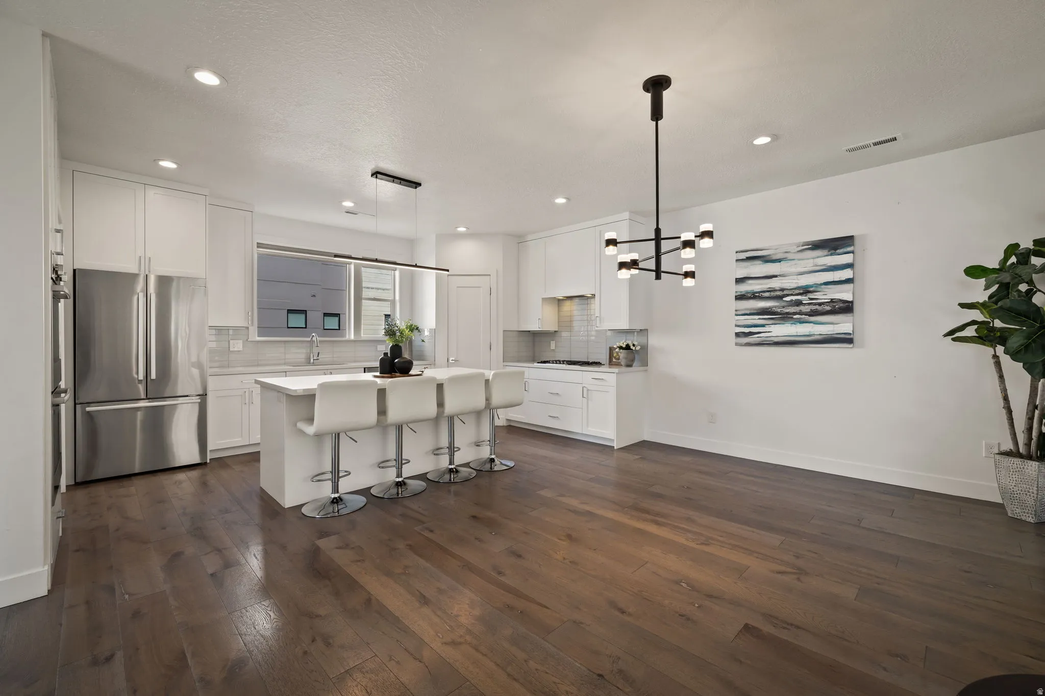 Kitchen featuring a breakfast bar, a center island, stainless steel appliances, white cabinets, and dark wood-style flooring
