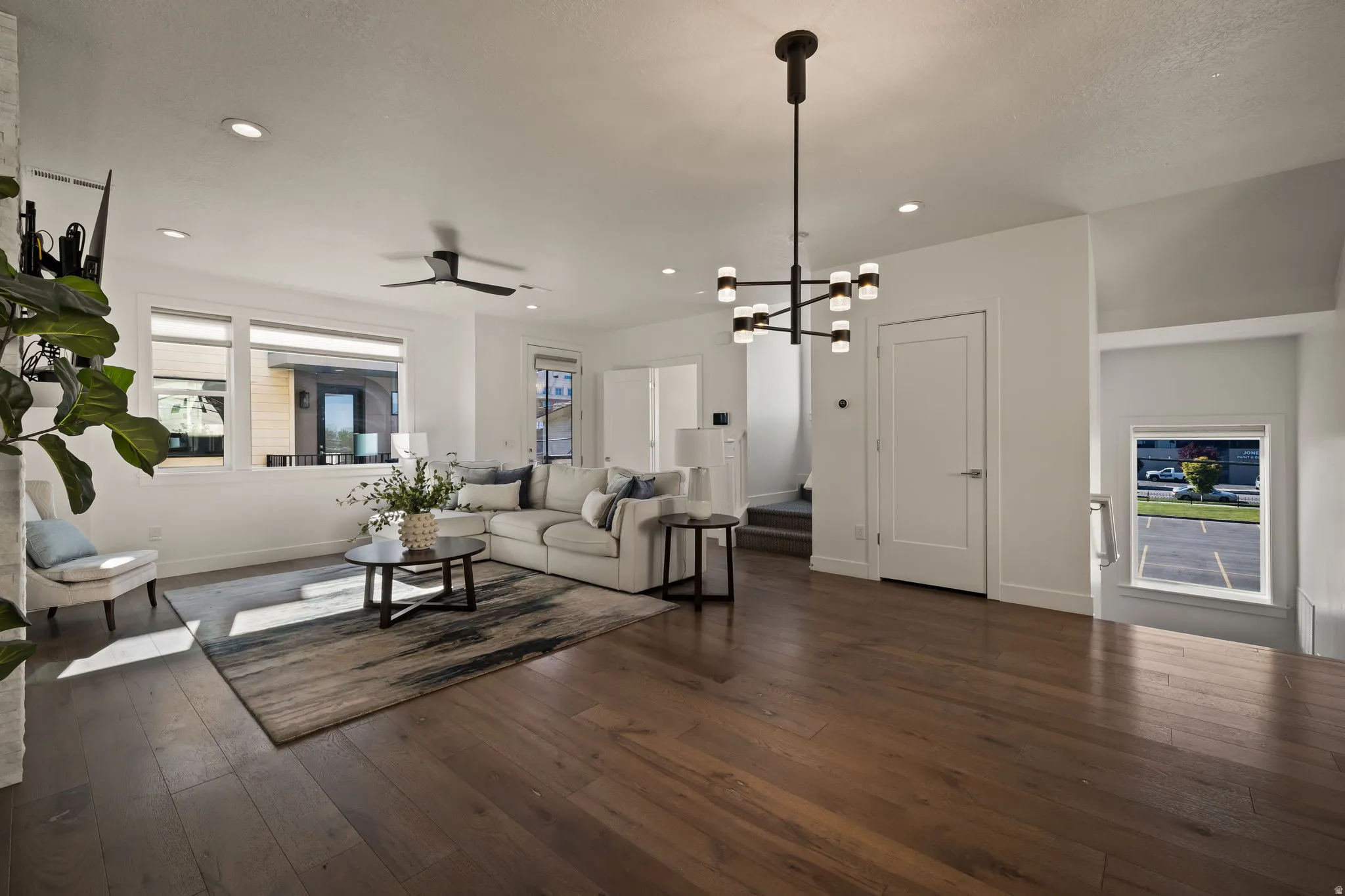 Living area with dark wood finished floors, ceiling fan, and suspended lighting