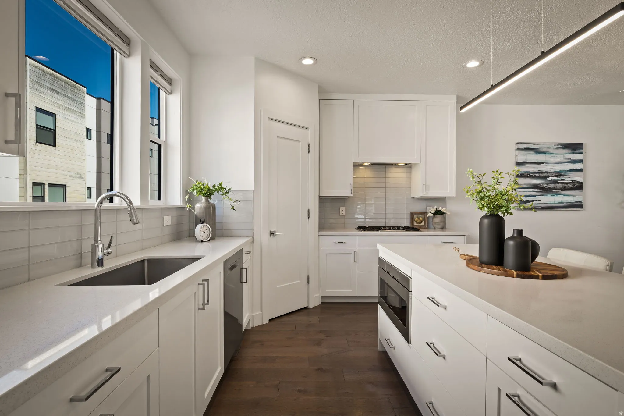 Kitchen with white cabinets, dark wood finished floors, recessed lighting, decorative backsplash, and stainless steel appliances