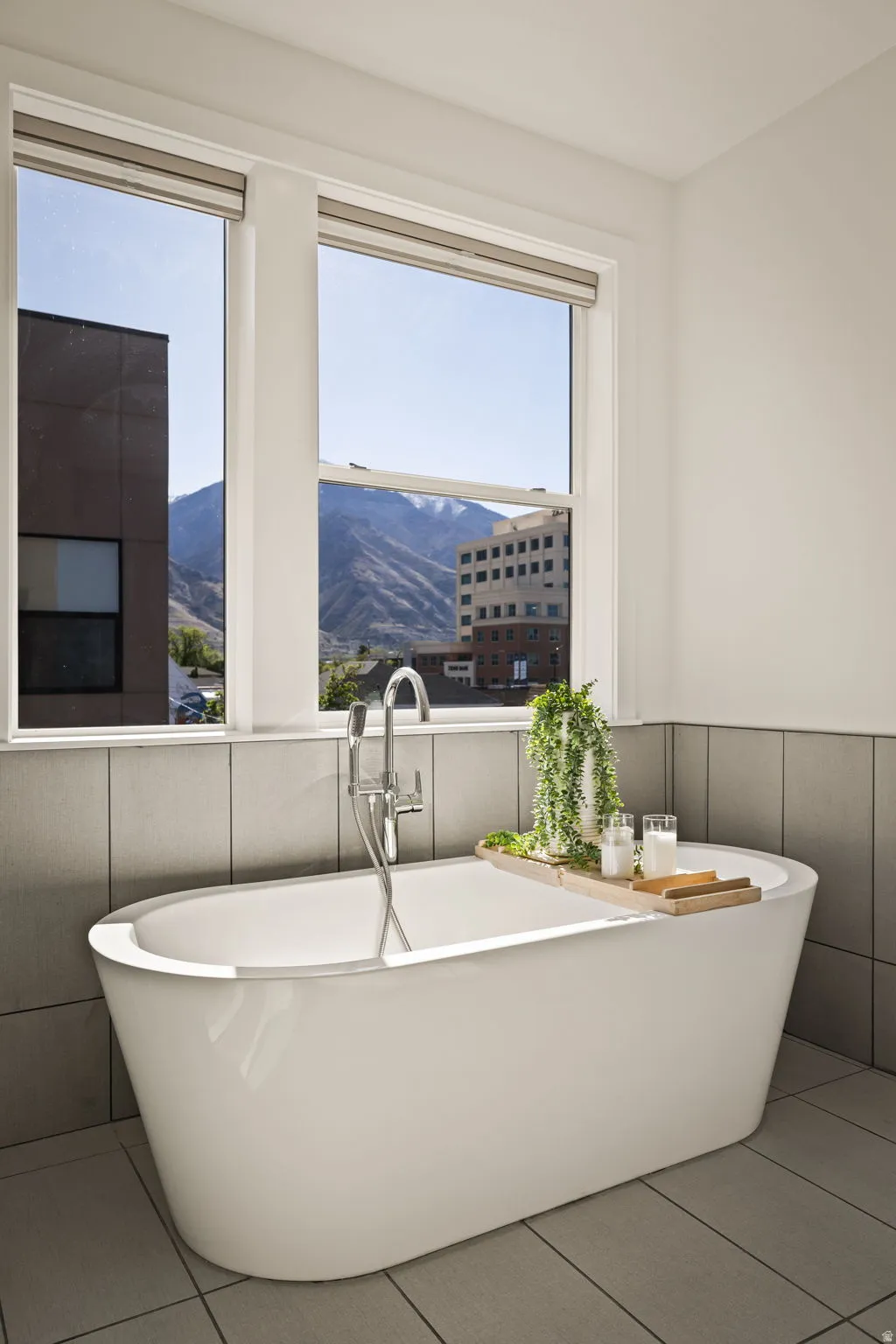 Bathroom featuring a freestanding bath, a mountain view, a wainscoted wall, and tile patterned flooring