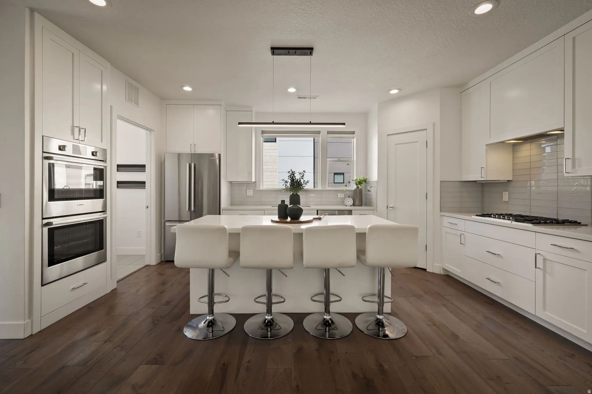 Kitchen featuring stainless steel appliances, white cabinetry, dark wood-style floors, a breakfast bar, and a textured ceiling