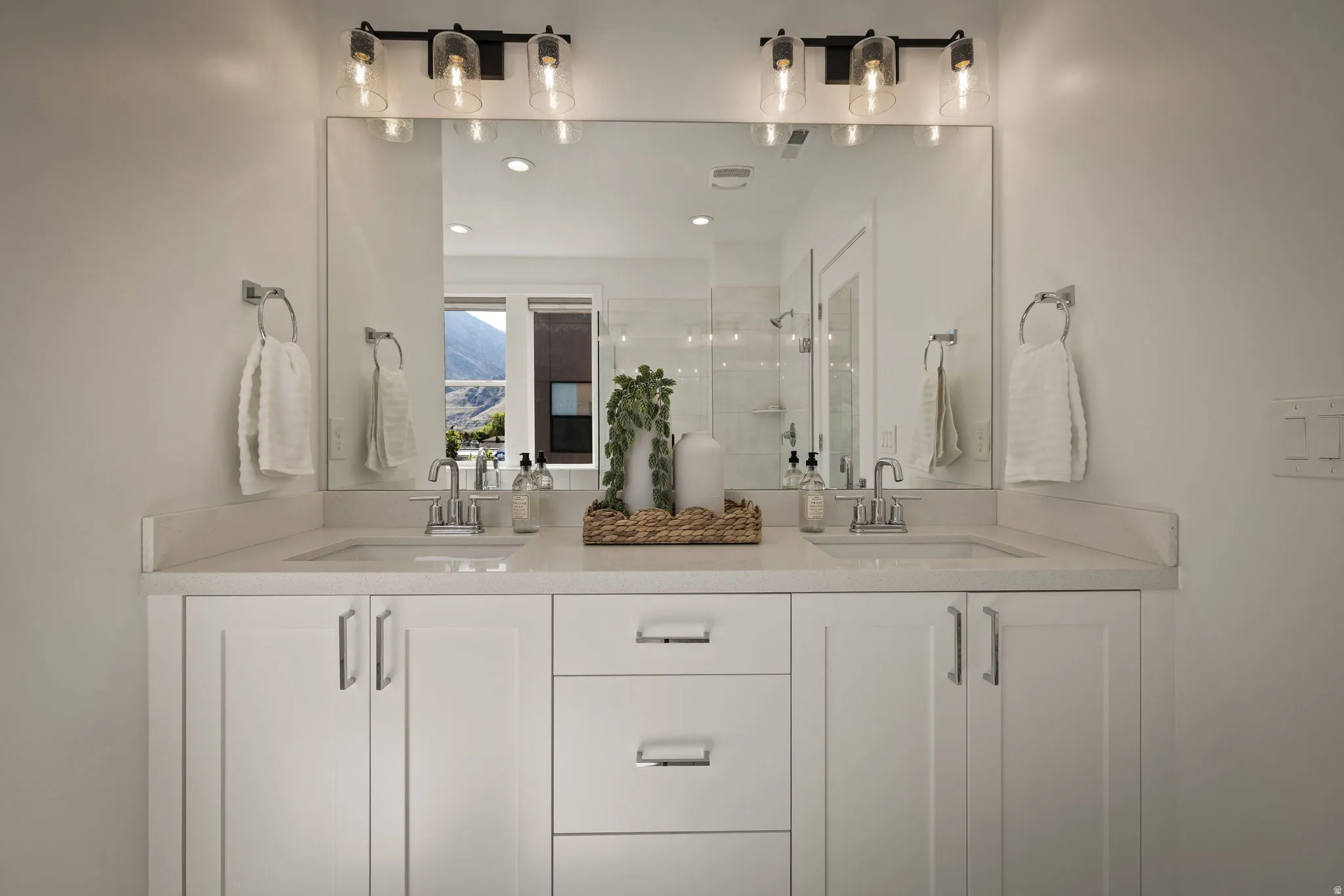Bathroom featuring a shower stall, double vanity, and recessed lighting