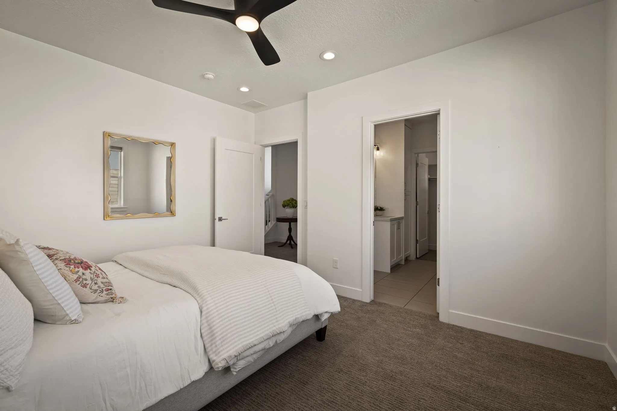 Carpeted bedroom featuring a ceiling fan, recessed lighting, and ensuite bath