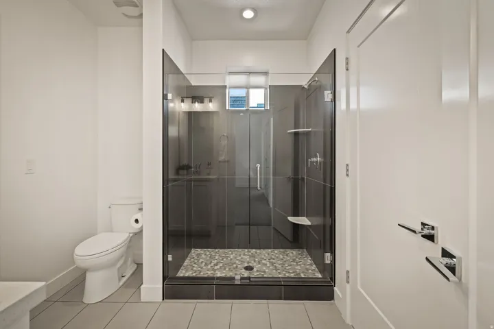 Full bath with a shower stall and light tile patterned floors