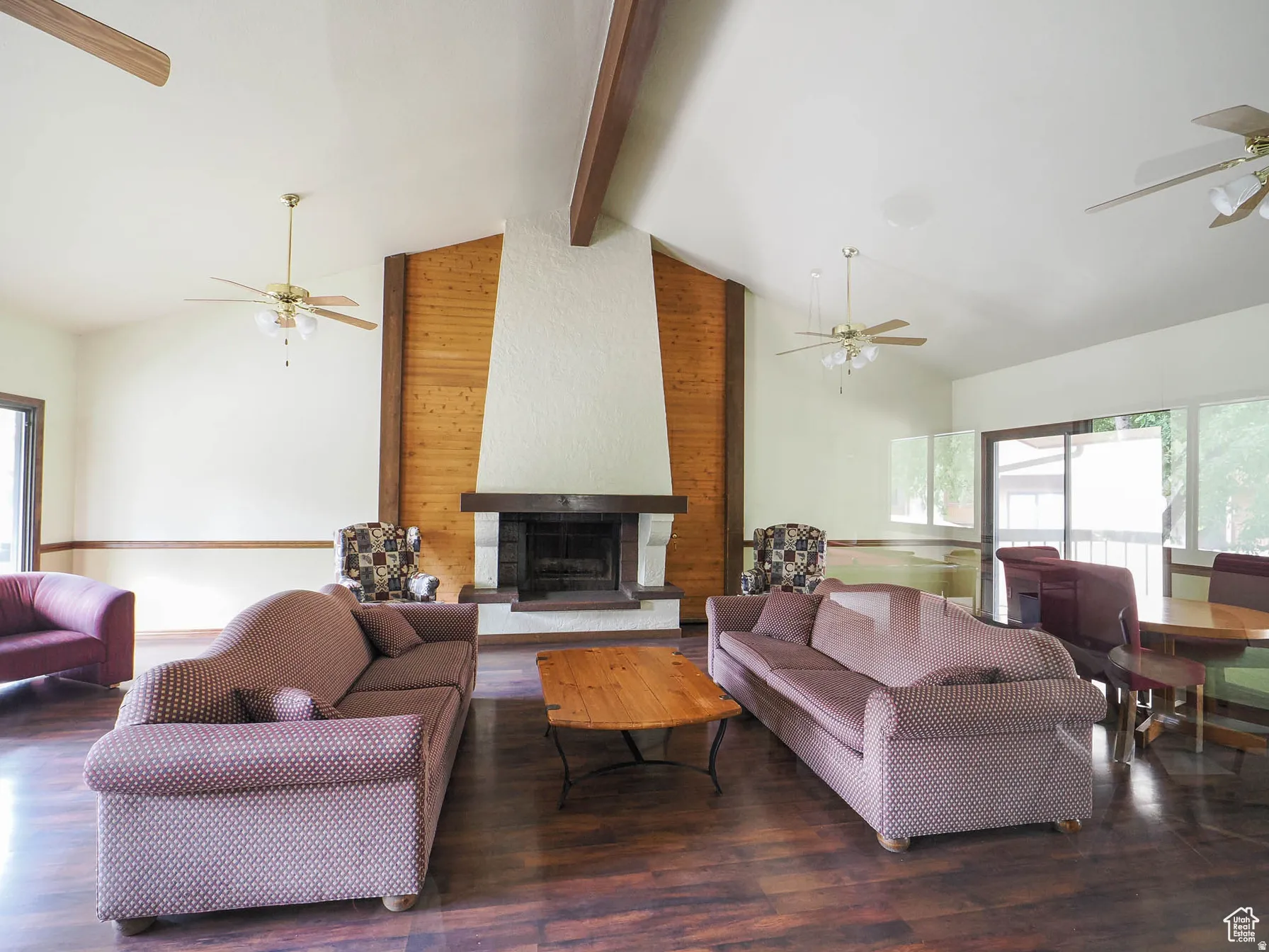 Spacious living area featuring a prominent floor-to-ceiling fireplace with a rustic wood mantle and stone hearth