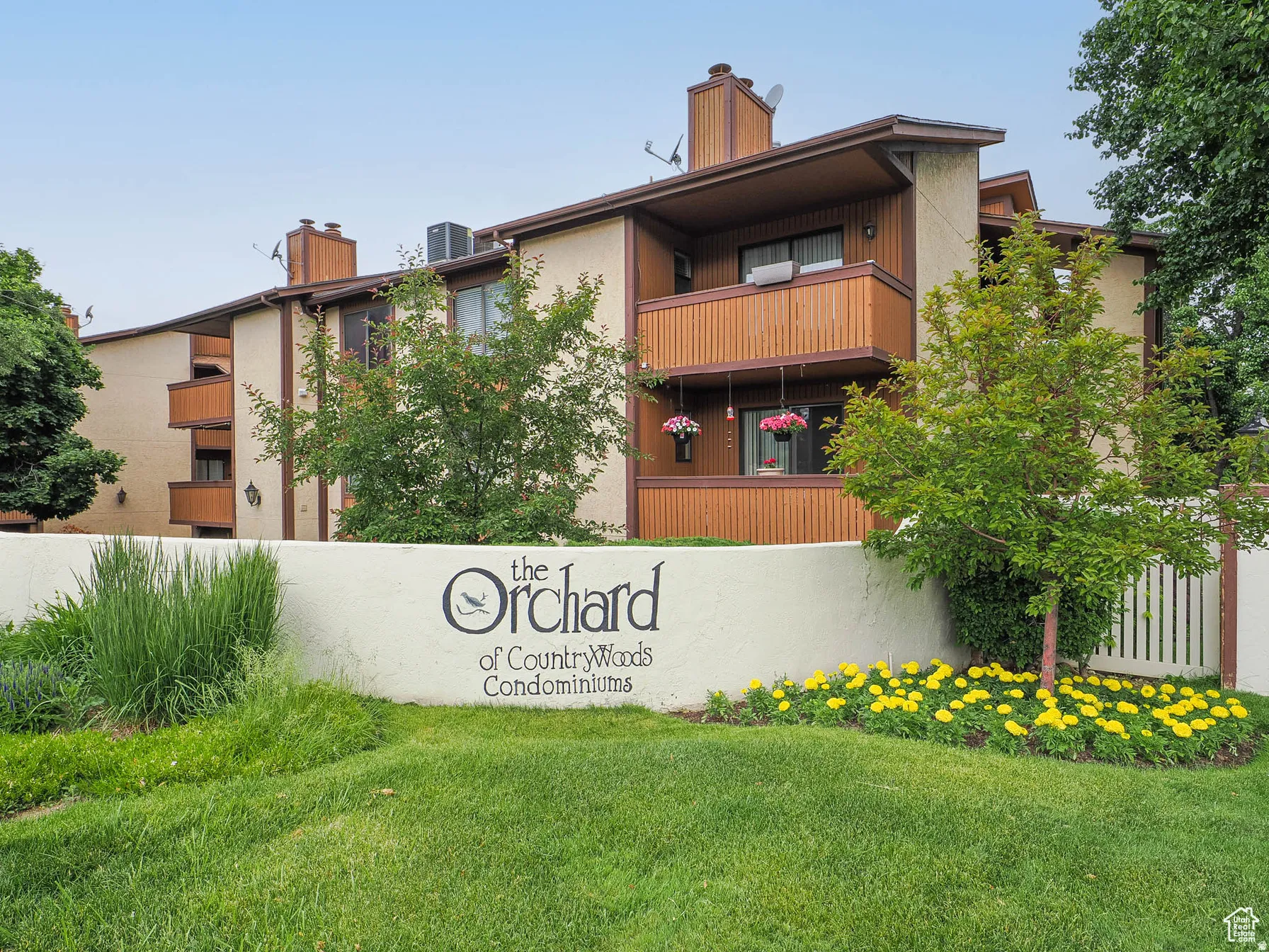 Multi-story condominium building featuring light-colored stucco and brown wood-panel siding