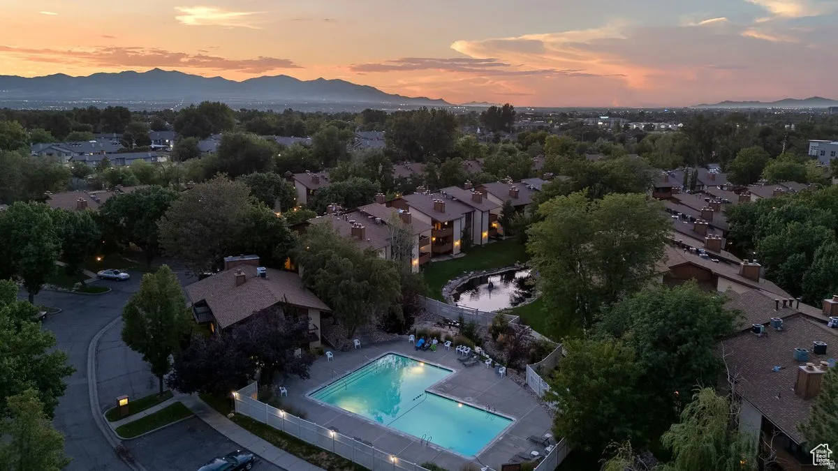 Expansive community featuring a swimming pool, mature trees, and a tranquil pond