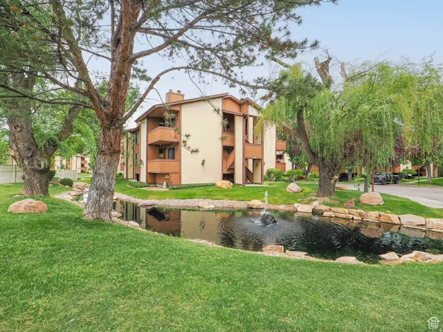 Lush green lawn with a rock-lined pond featuring a fountain