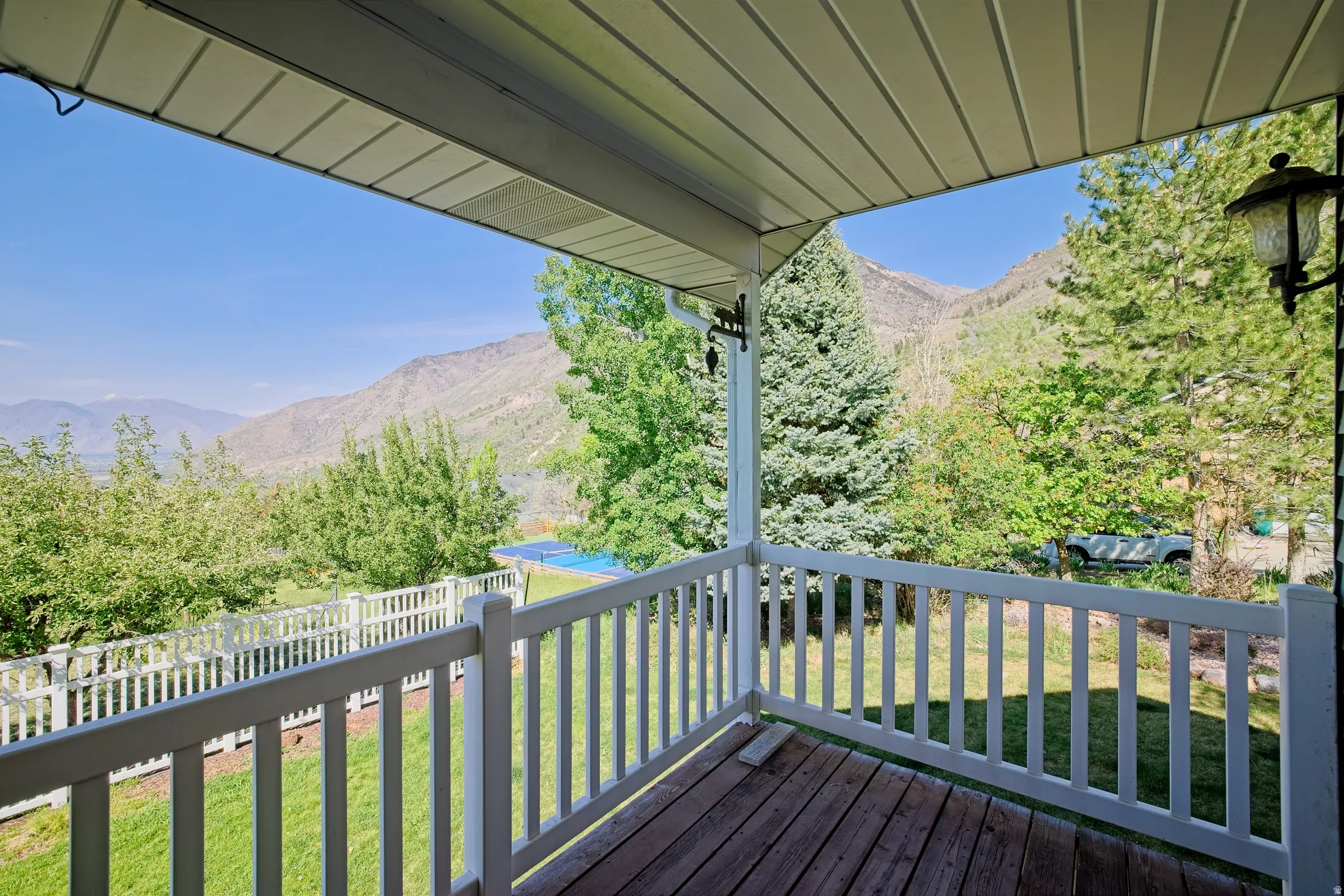 Covered porch with wood-finish flooring and white railing