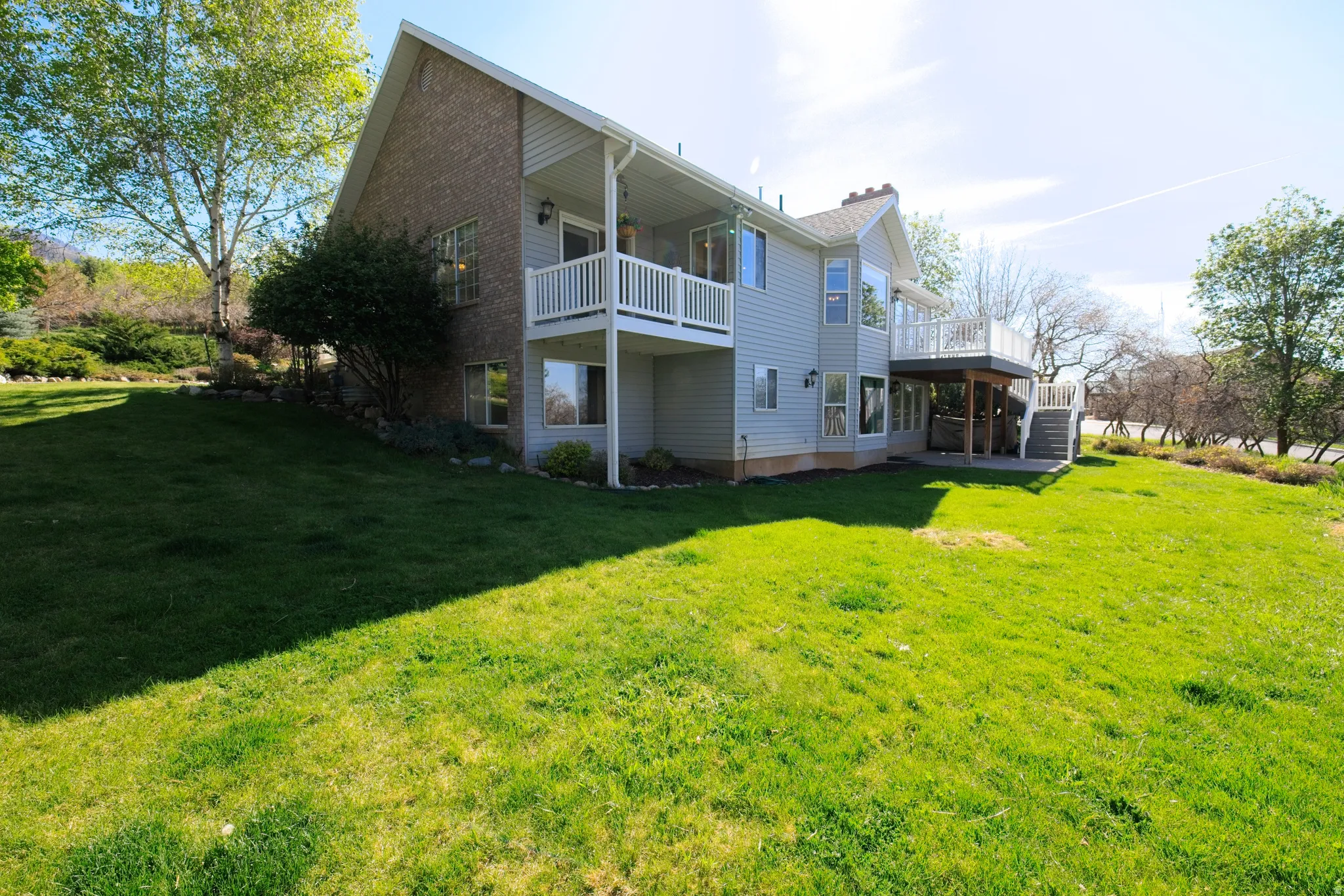 Expansive green lawn bordering a two-story residence with a brick and siding exterior