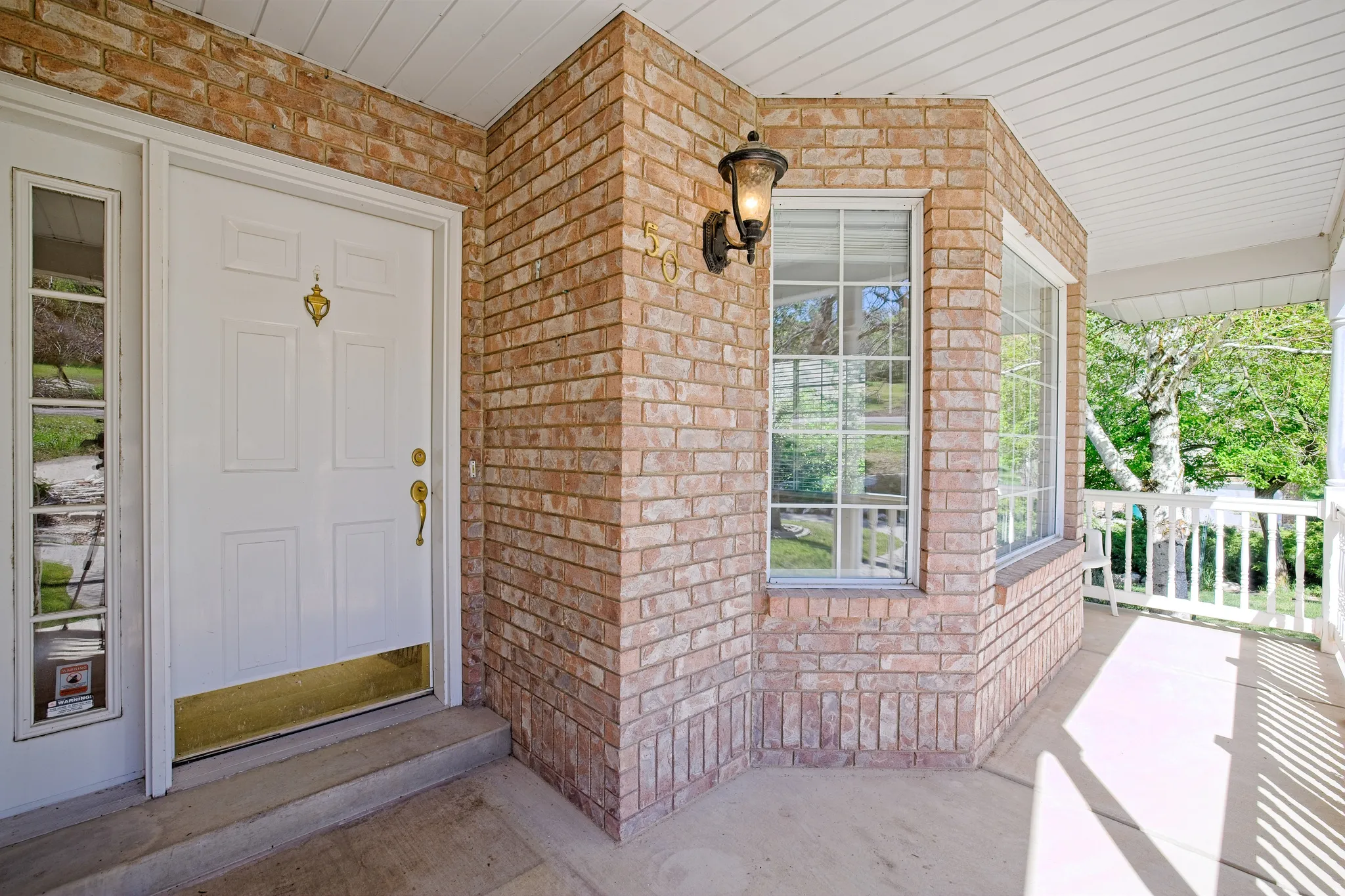 Inviting brick exterior featuring a white paneled entry door with sidelite, a decorative brass door knocker, and coordinating hardware