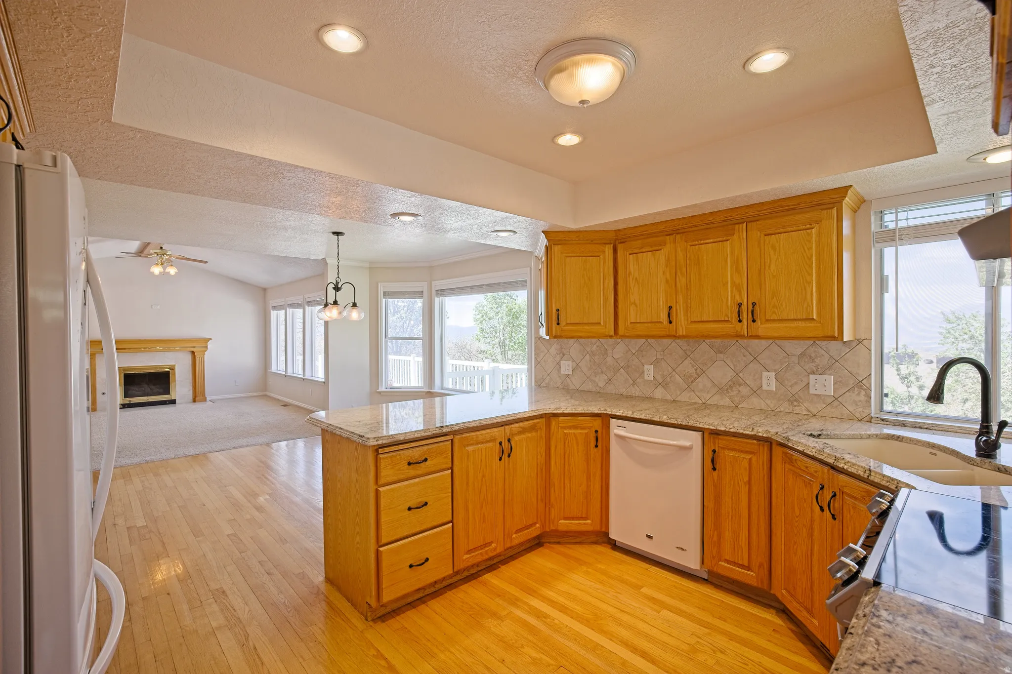 Kitchen featuring wood-finish flooring, light wood cabinetry, stone countertops, and a tiled backsplash