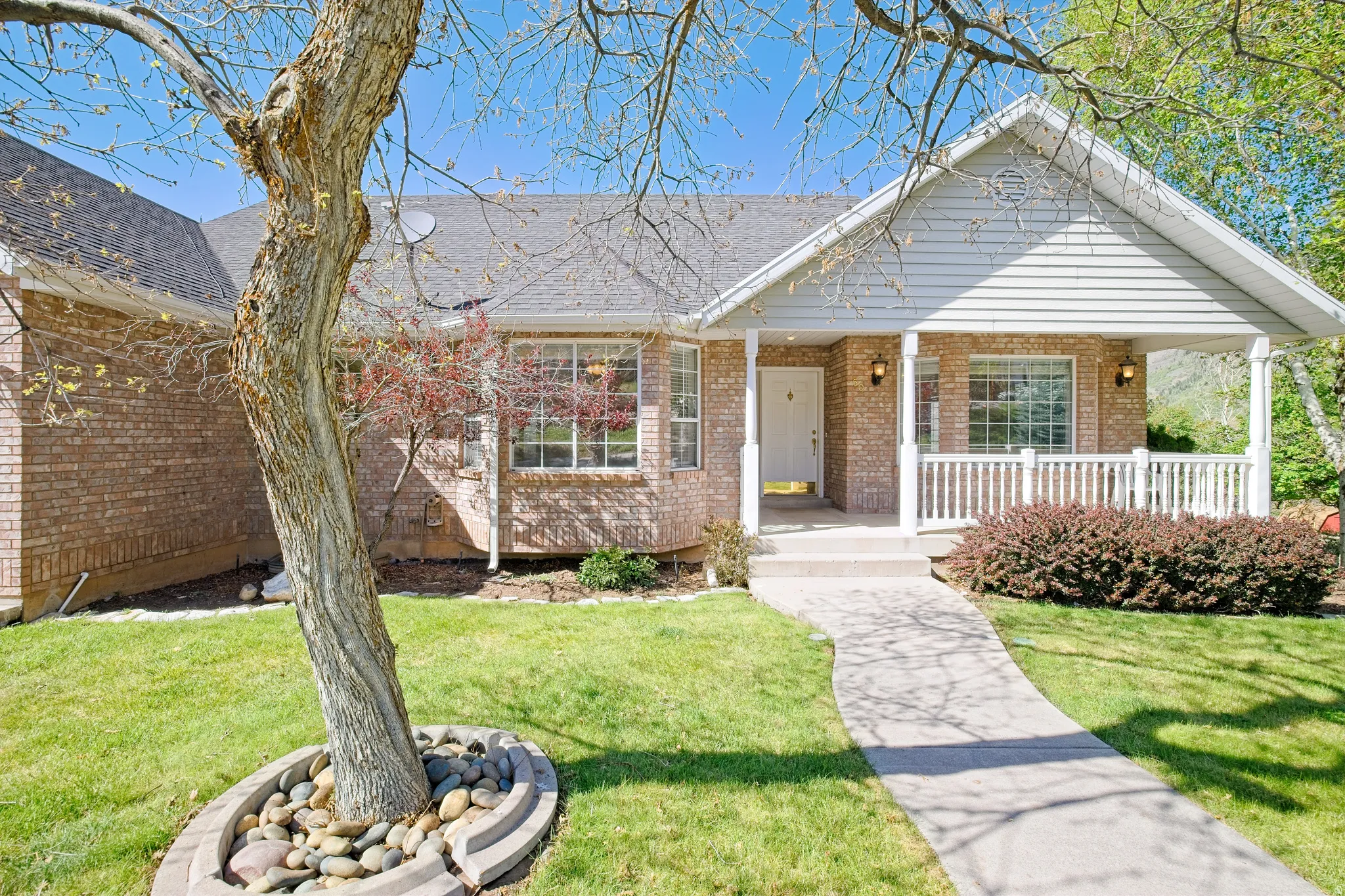 Brick exterior with white siding accents and a covered front porch featuring white railings