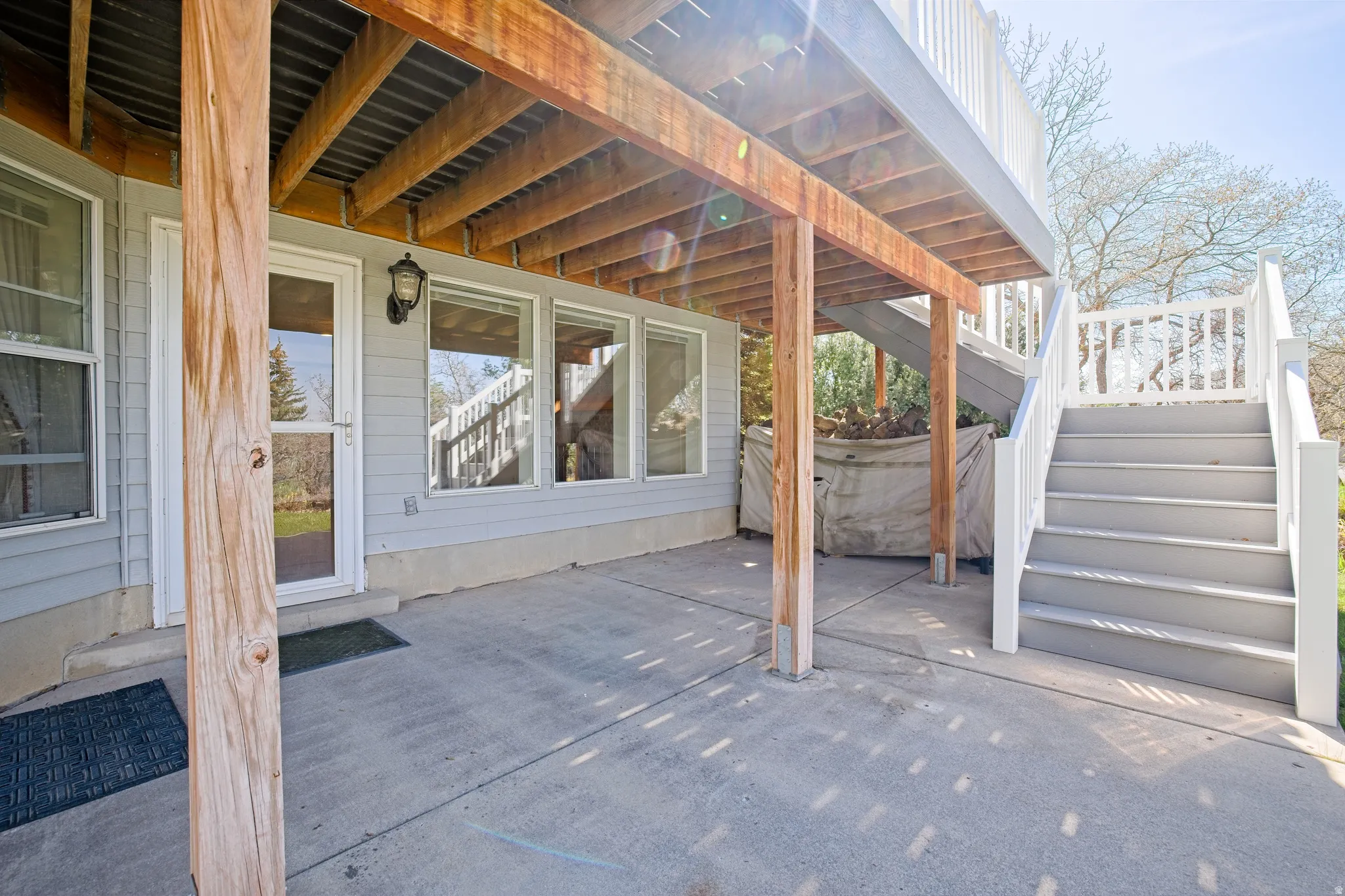 Covered concrete patio with direct access to interior via a glass-paneled door. Stairs leading to Level 1.