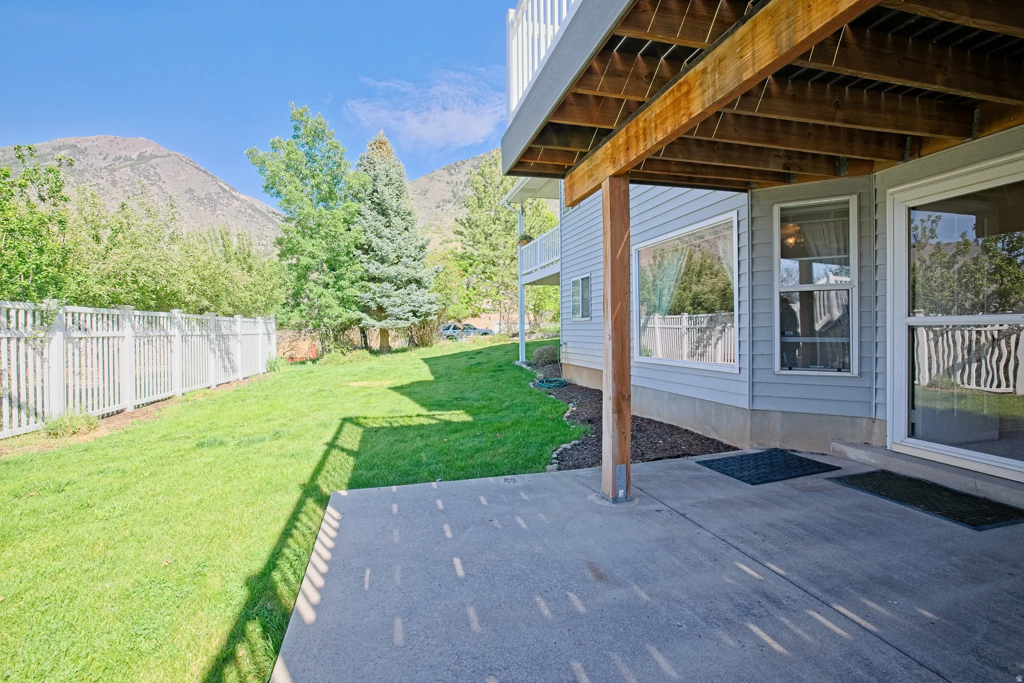Expansive concrete patio with overhead deck structure. Part of the large yard.