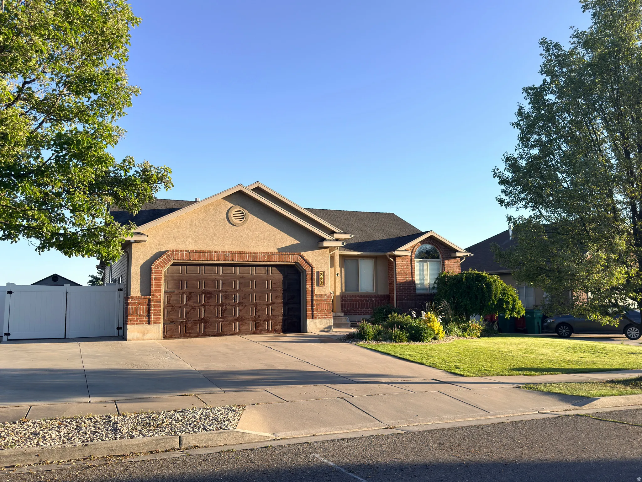 Ranch-style residence featuring a textured stucco exterior with brick accents and a dark shingle roof