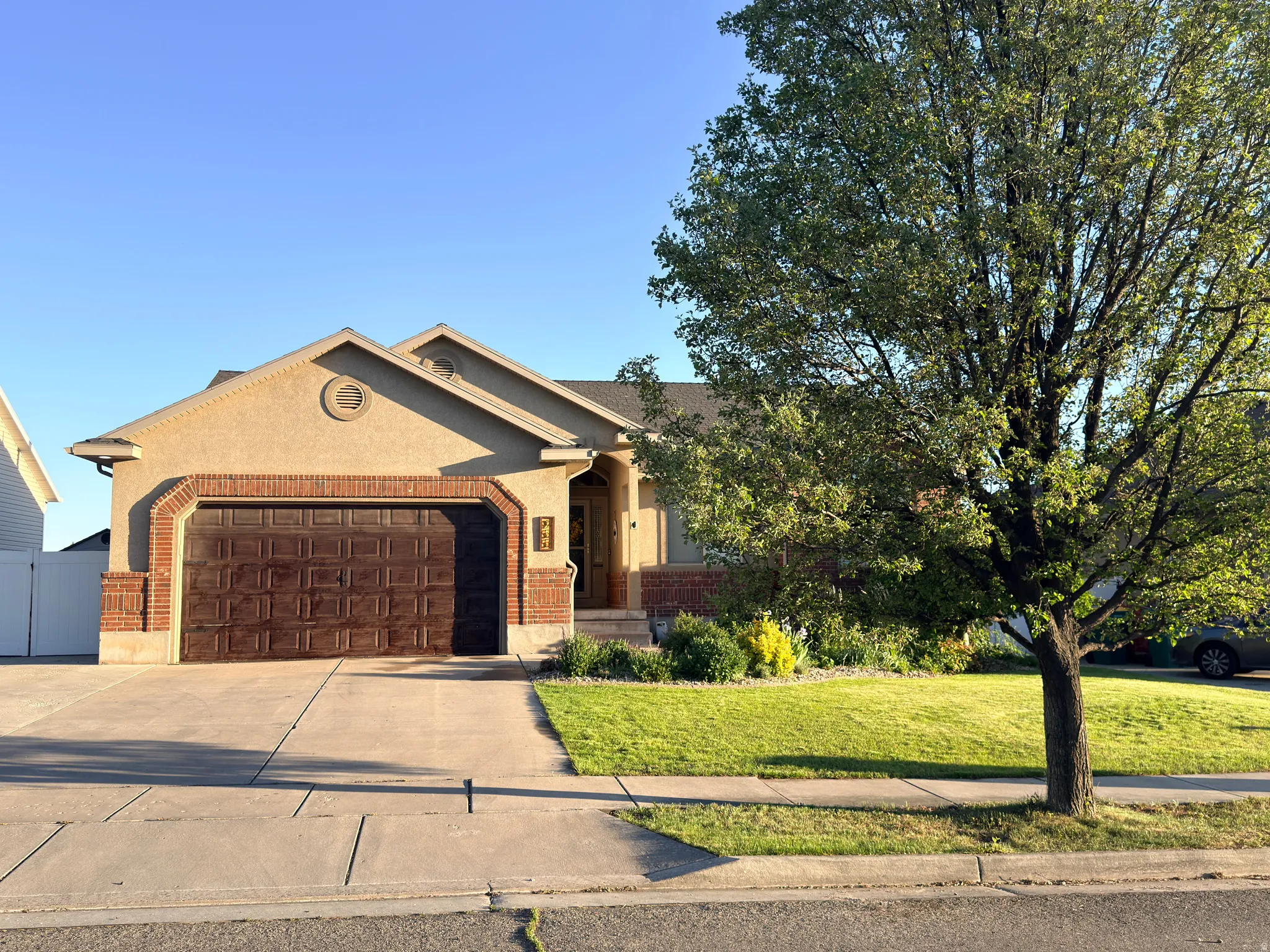 Stucco exterior residence featuring a brick garage surround, arched garage door, and a circular accent window