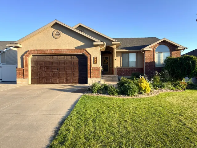 Stucco and brick exterior with an arched window, a paneled garage door, and a concrete driveway