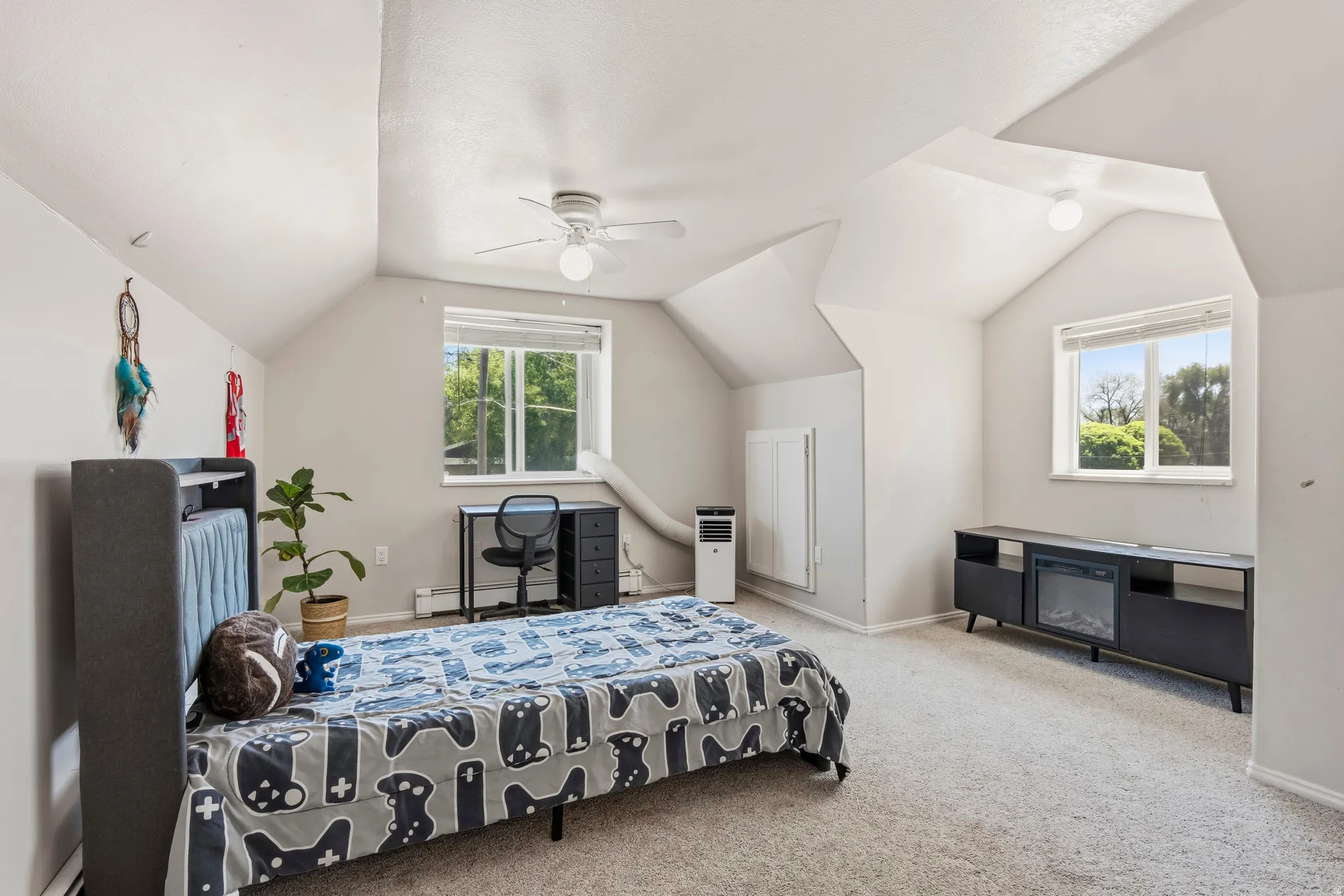 Expansive room featuring vaulted ceilings, a ceiling fan, and carpeted flooring