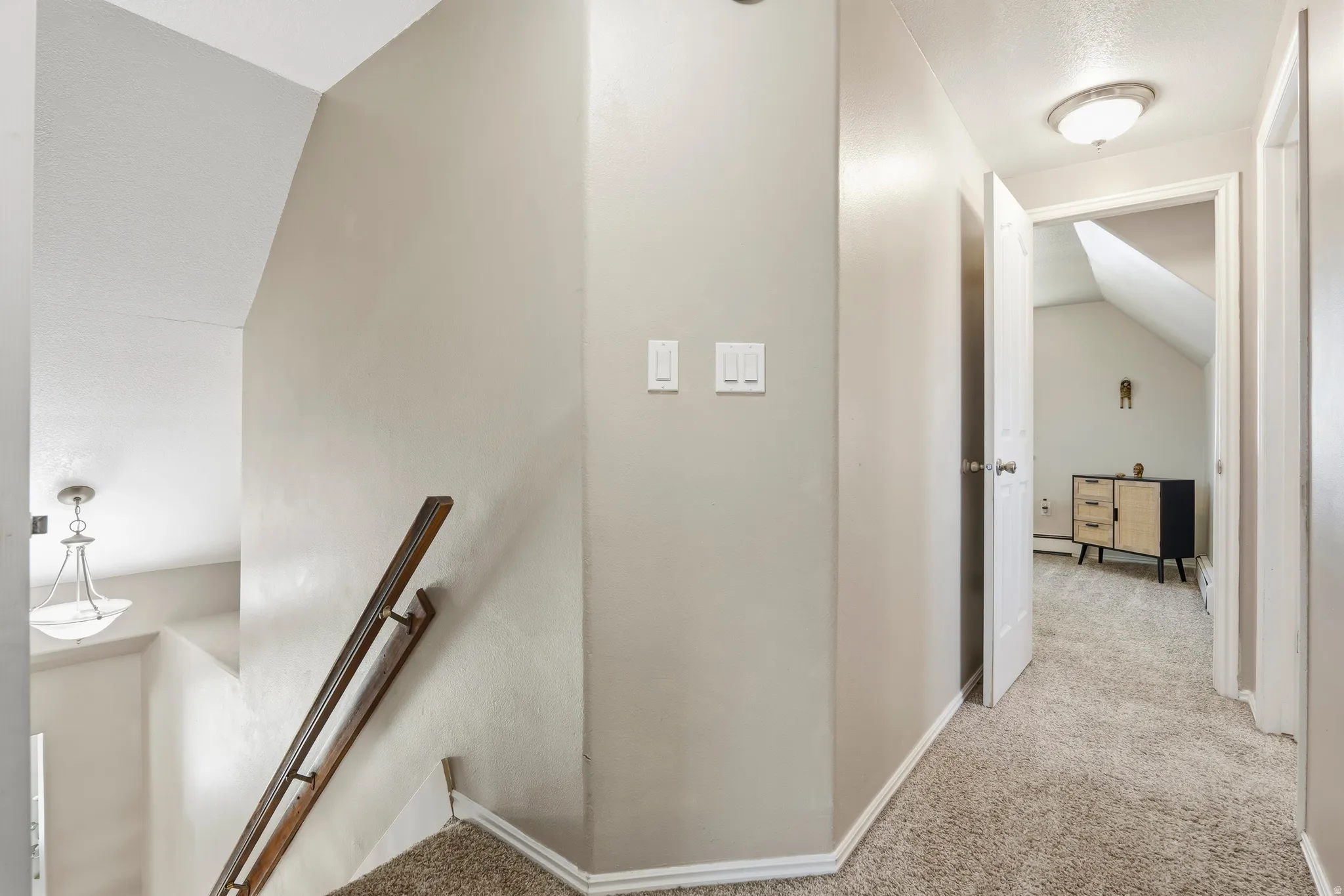 Upper-level hallway with neutral wall tones and carpeted flooring