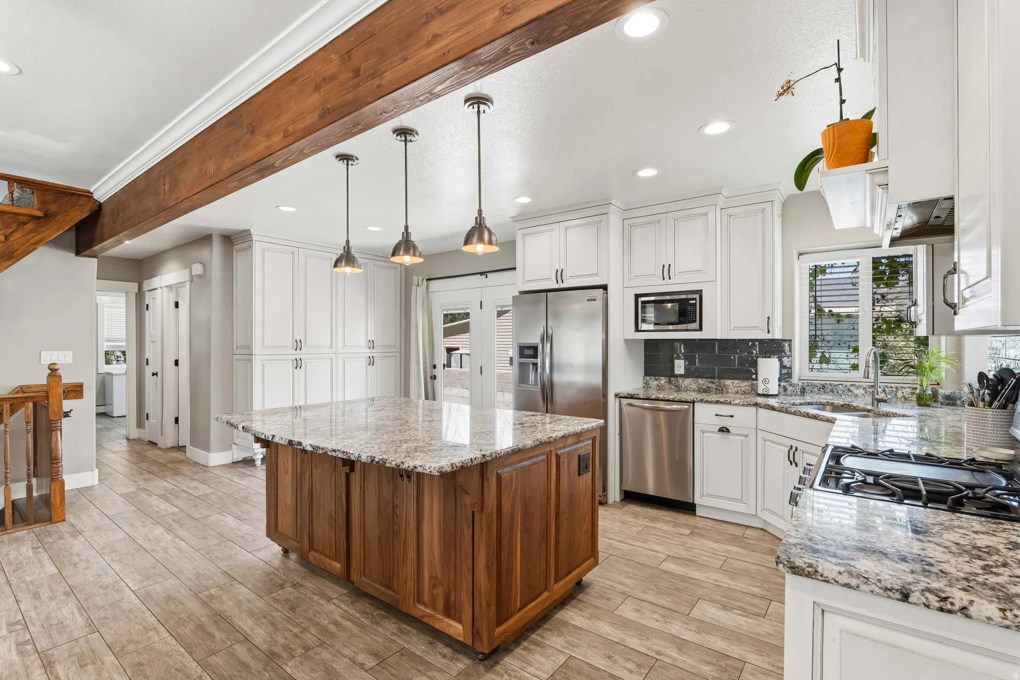 Kitchen featuring a large wood-finish island with a granite countertop, white cabinetry, stainless steel appliances, and wood-finish flooring