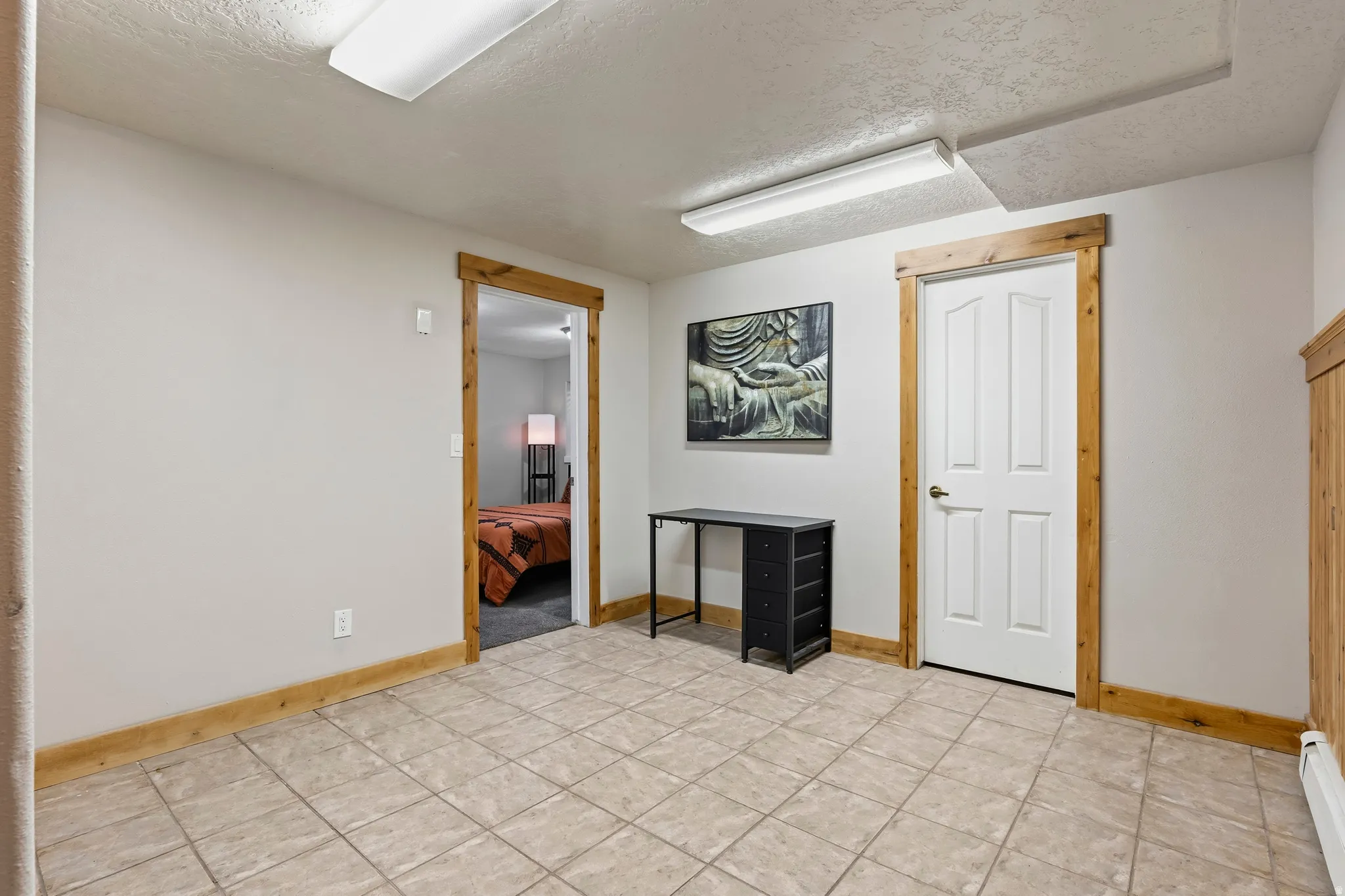 Neutral-toned ceramic tile flooring with contrasting wood trim and doors