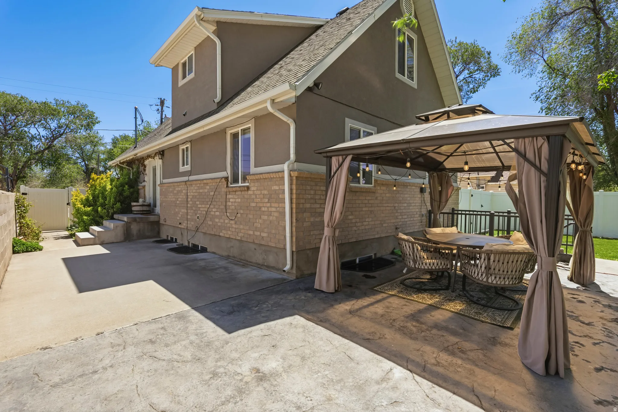 Stucco and brick exterior featuring a patterned concrete patio