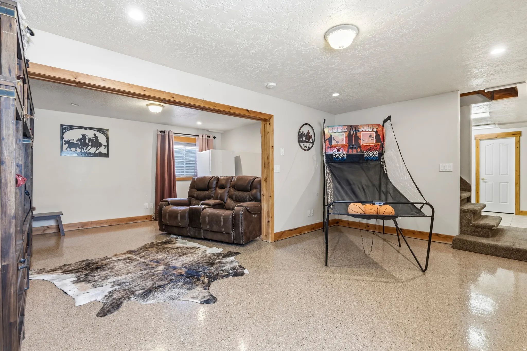 Recessed lighting illuminates an open space with light-colored walls and exposed wood trim
