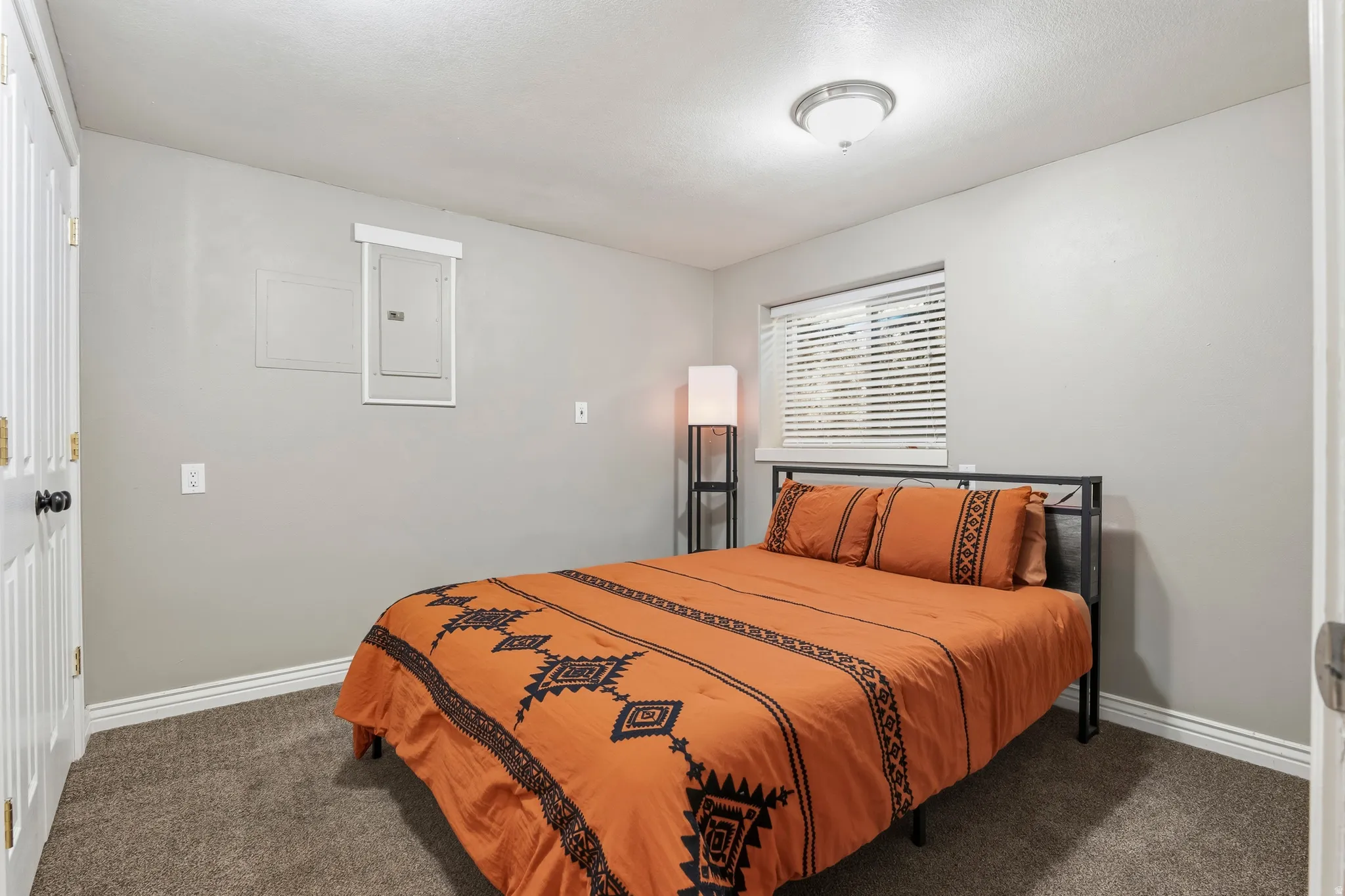 Carpeted room with a window featuring horizontal blinds, a white trim package, and a flush-mount ceiling light fixture