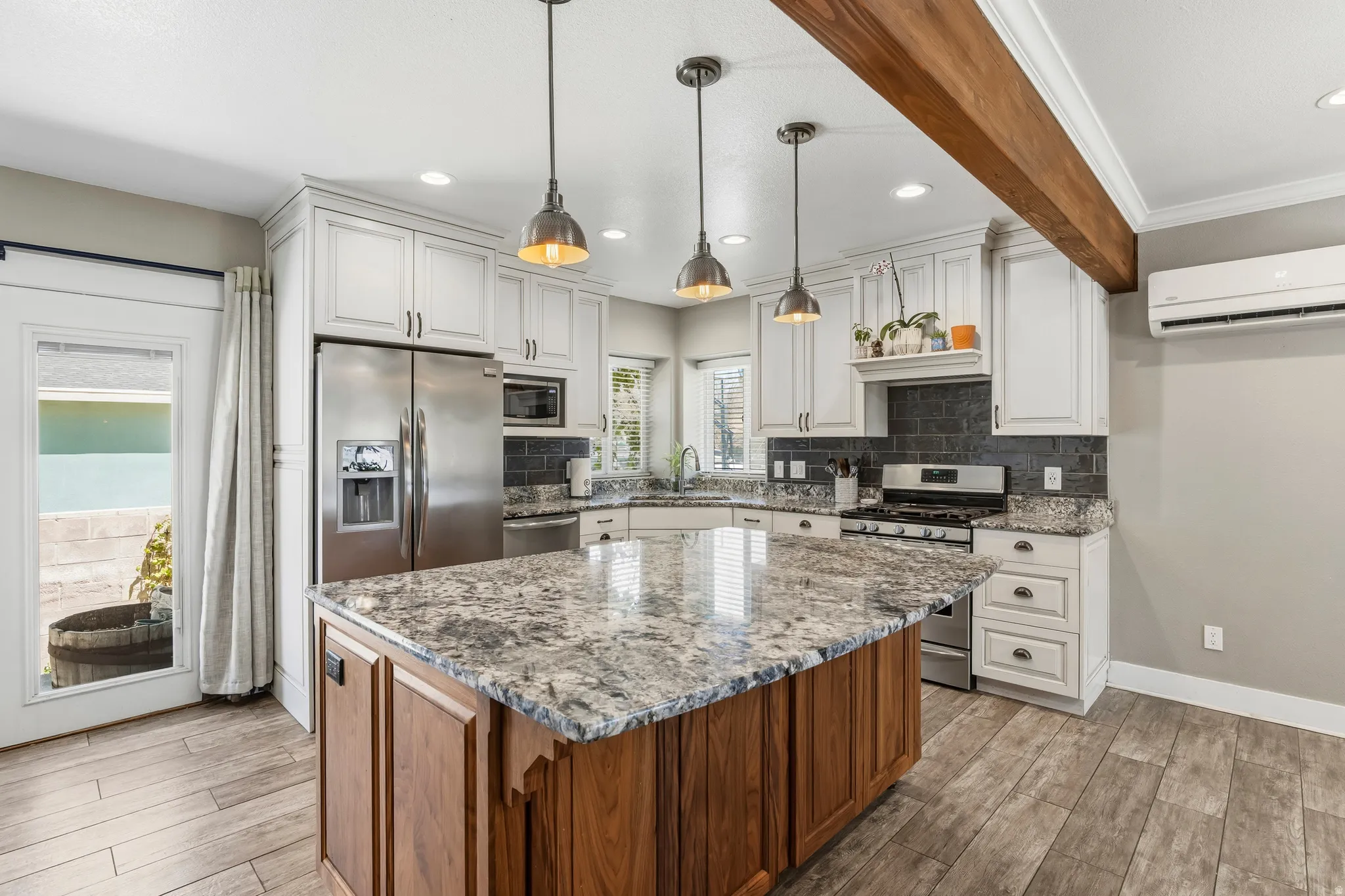Kitchen featuring a central island with granite countertop, white cabinetry, and stainless steel appliances