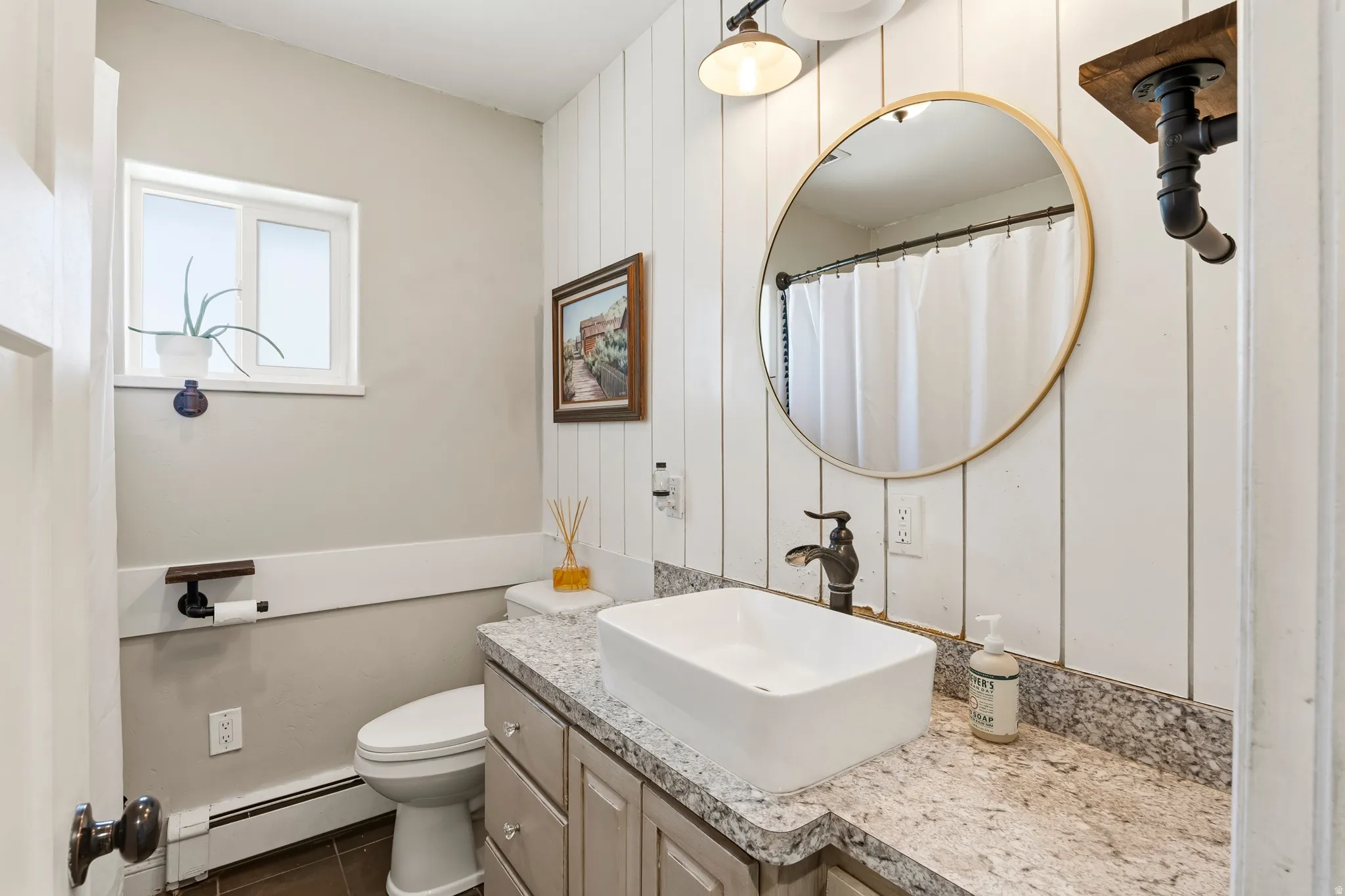 Bathroom featuring a vessel sink with a dark bronze faucet, a speckled countertop, and wood-finish vanity cabinetry