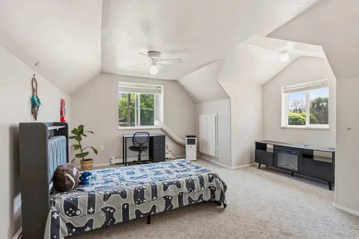 Expansive room featuring vaulted ceilings, a ceiling fan, and carpeted flooring