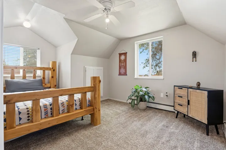 Vaulted ceiling room featuring carpet flooring, a window with horizontal blinds, and a ceiling fan with integrated lighting