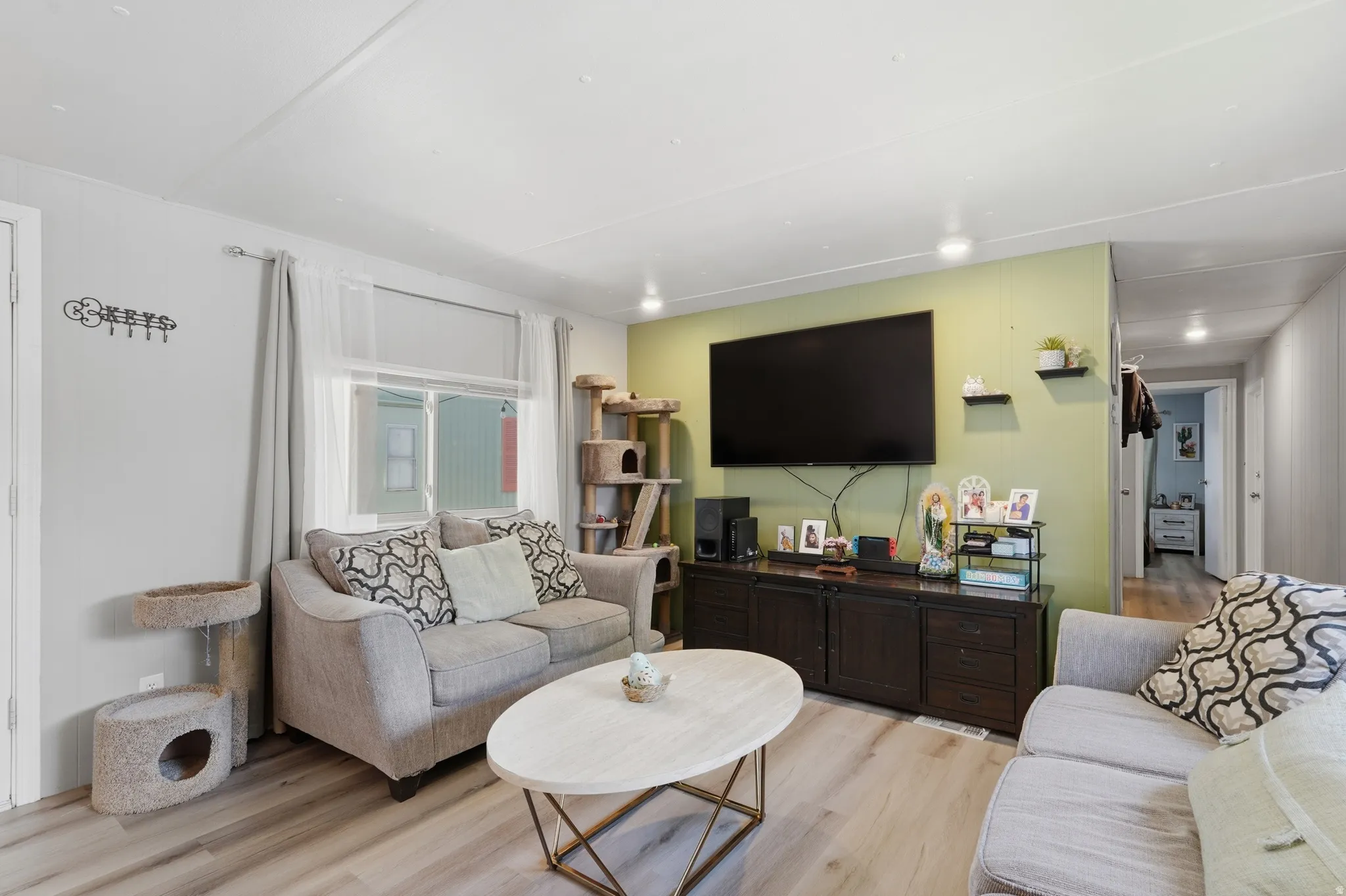 Living area featuring wood-finish flooring, recessed lighting, and a window with blinds and sheer curtains