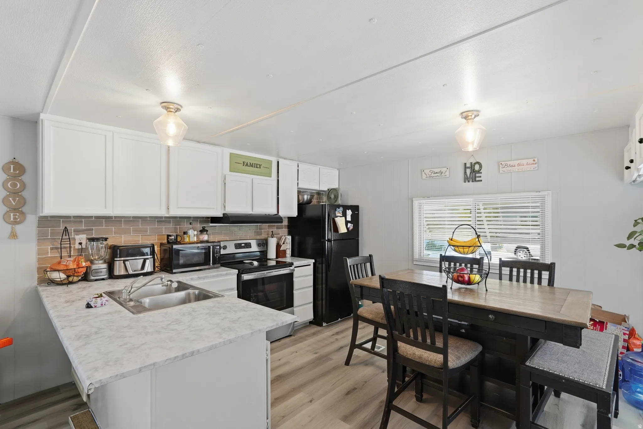 Kitchen featuring white cabinetry, a stainless steel double-basin sink, and a light-toned countertop