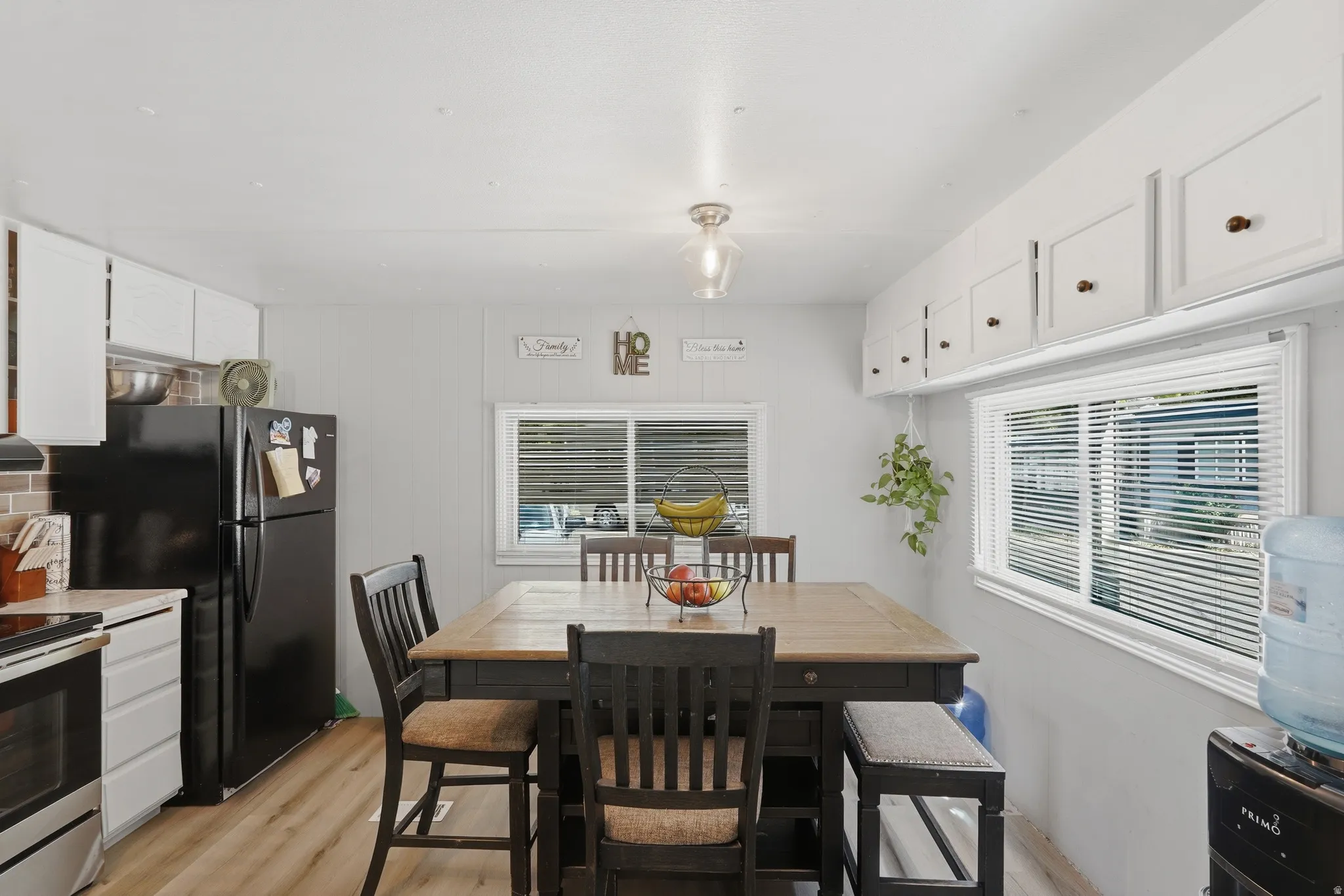 Kitchen area featuring wood-finish flooring, white cabinetry with contrasting hardware, and a window with blinds