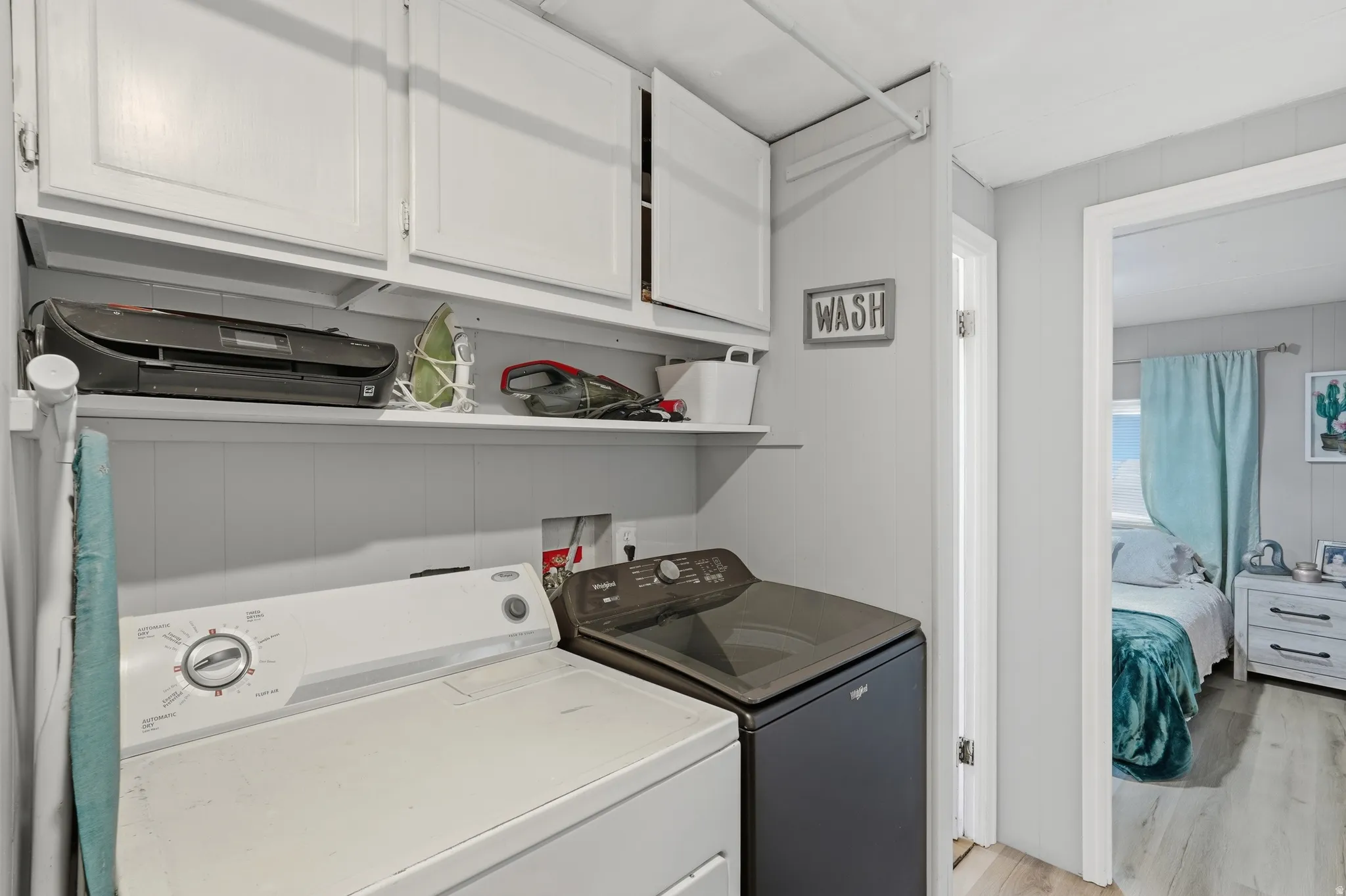 Laundry area featuring white cabinetry, a single floating shelf, and paneling on the lower wall