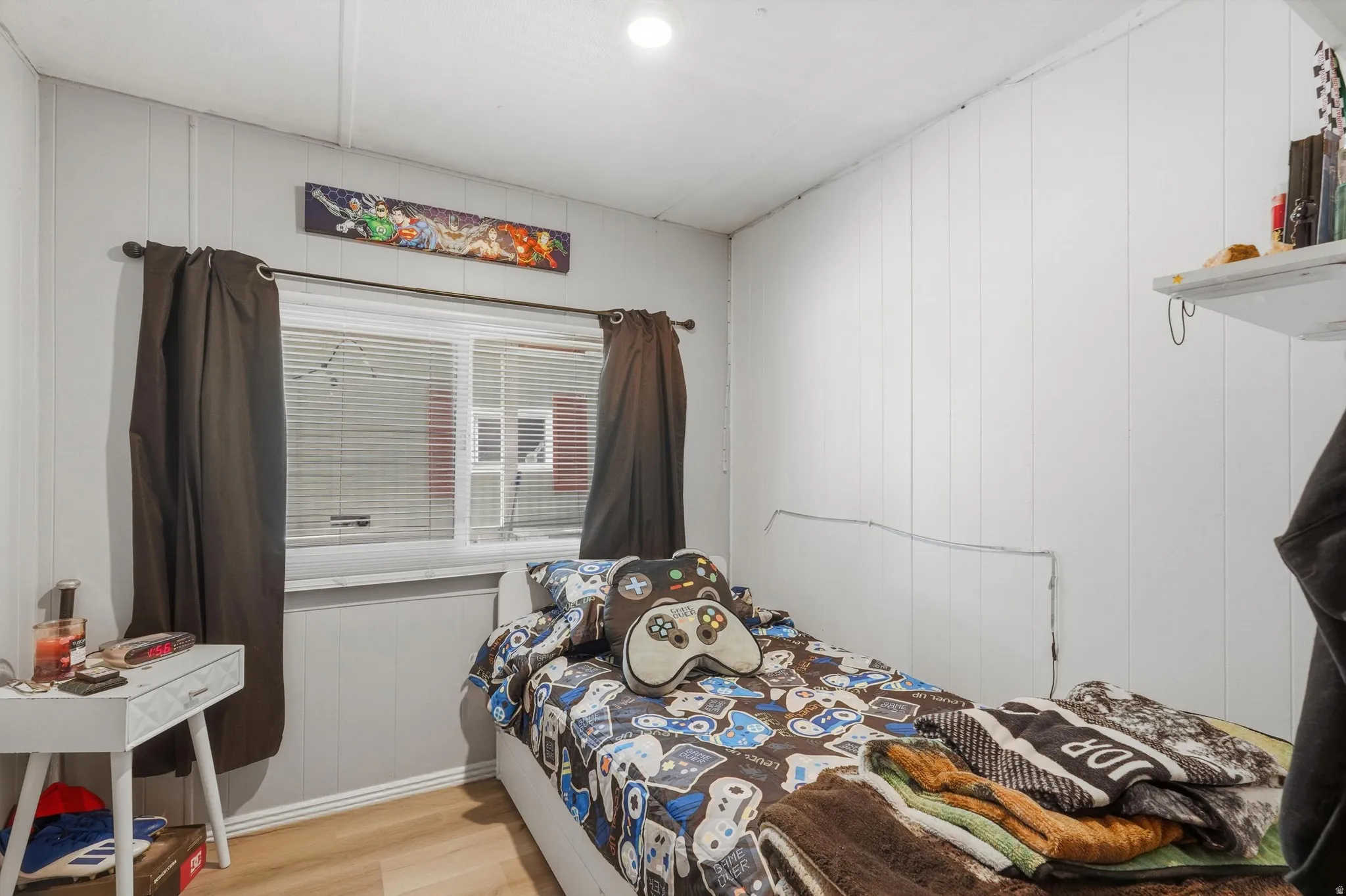 Room featuring wood-finish flooring, white vertical paneled walls, and a recessed ceiling light