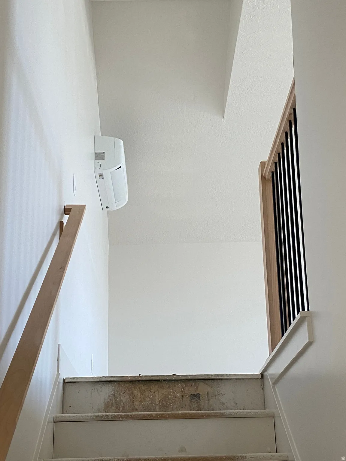 Staircase featuring light wood-finish handrails and a balustrade with black vertical spindles