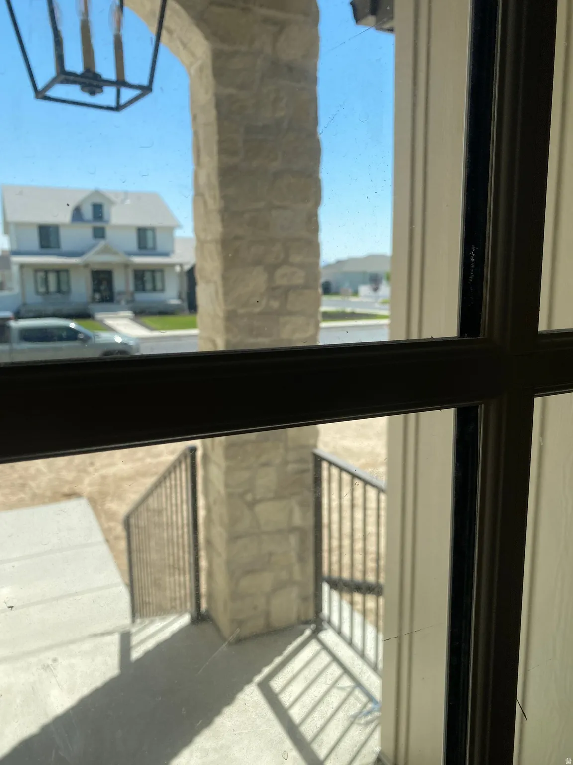 Stone archway entry featuring an exterior lantern light fixture, concrete steps, and dark metal railings